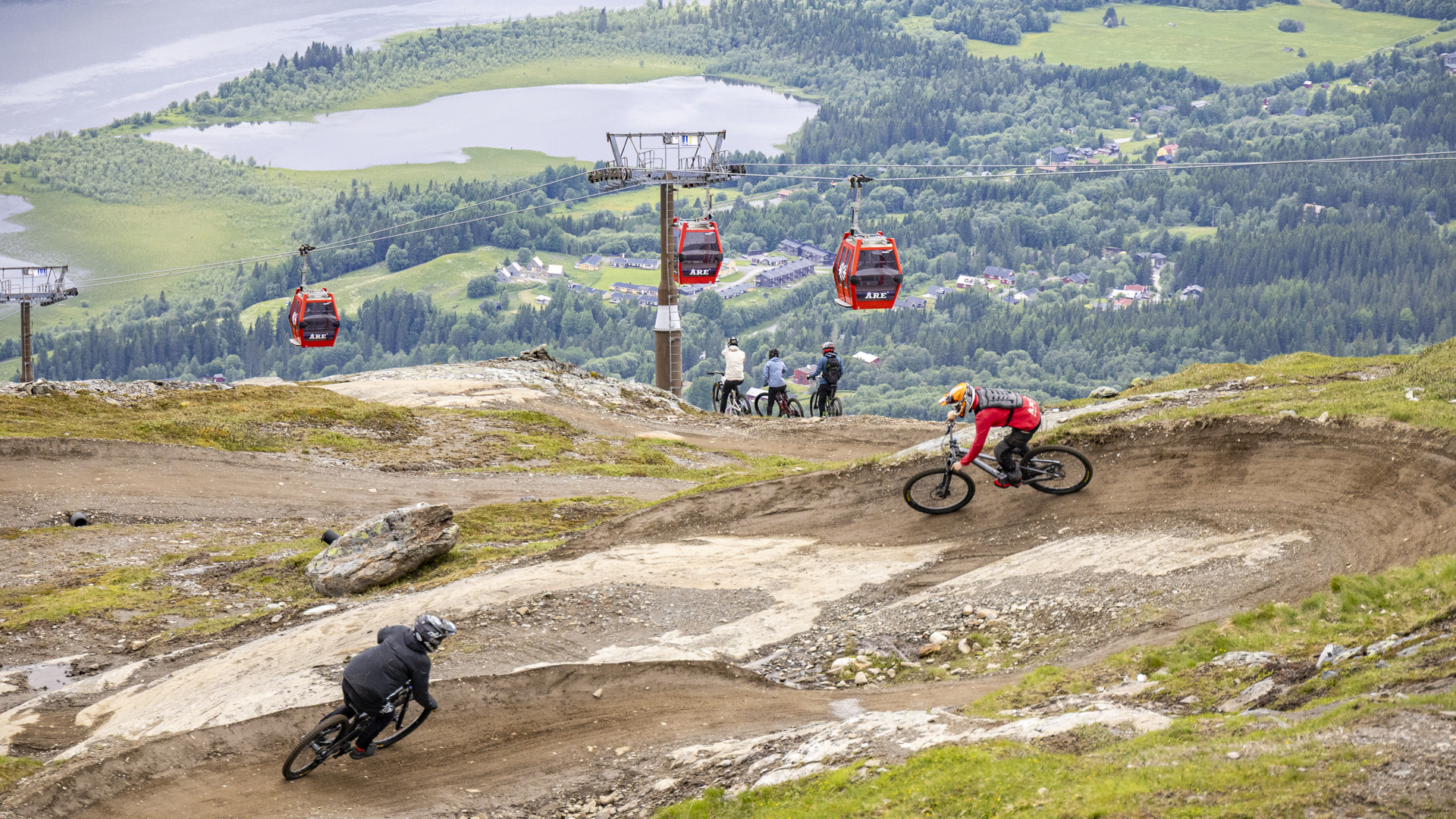 Venner på sykkelferie i Åre ser ned mot Åresjön. Gondolen i bakgrunn mens vennene tar en pause fra syklingen.