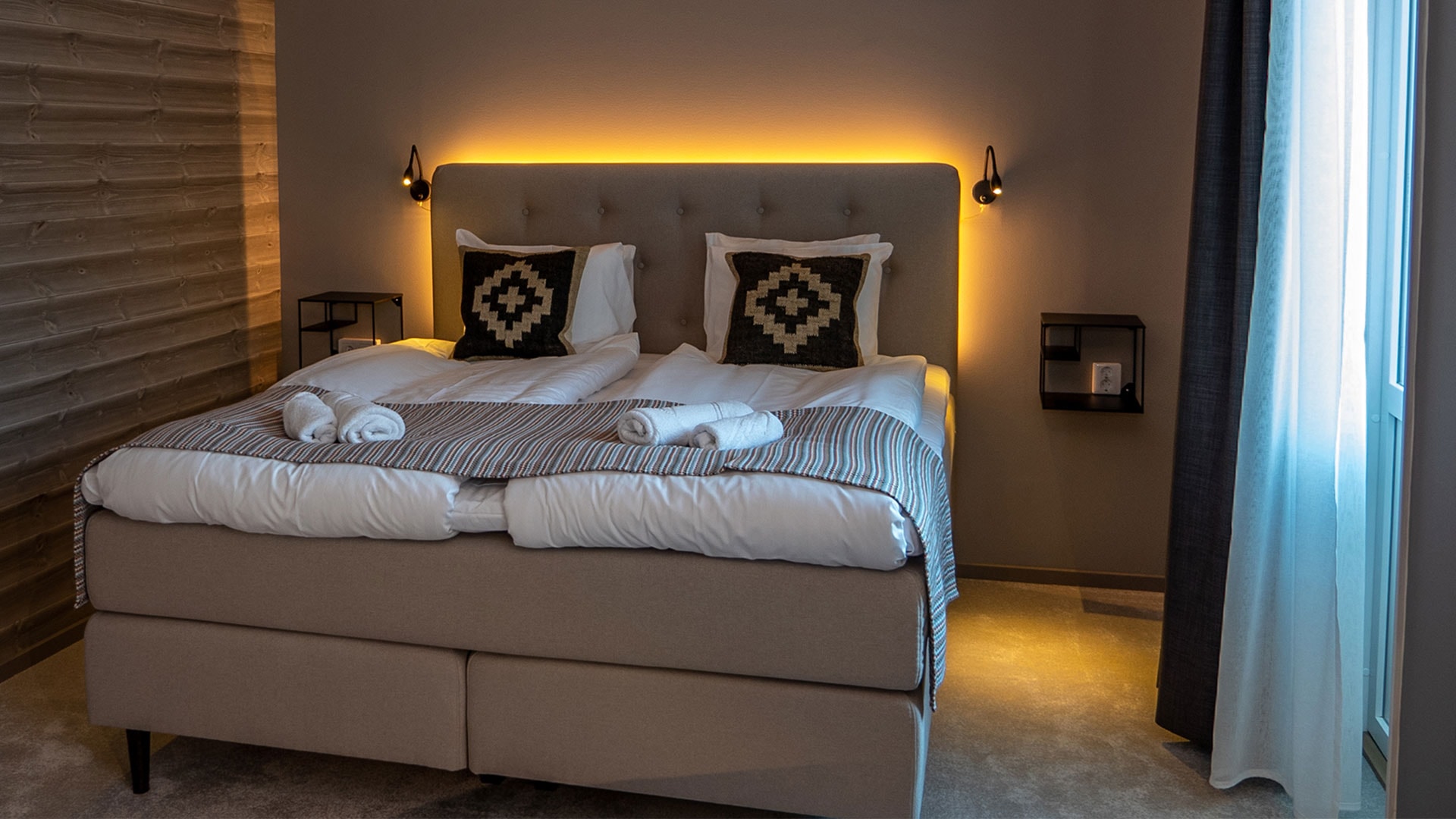 Modernt och mysigt hotellrum med dubbelsäng, elegant belysning och inredningsdetaljer