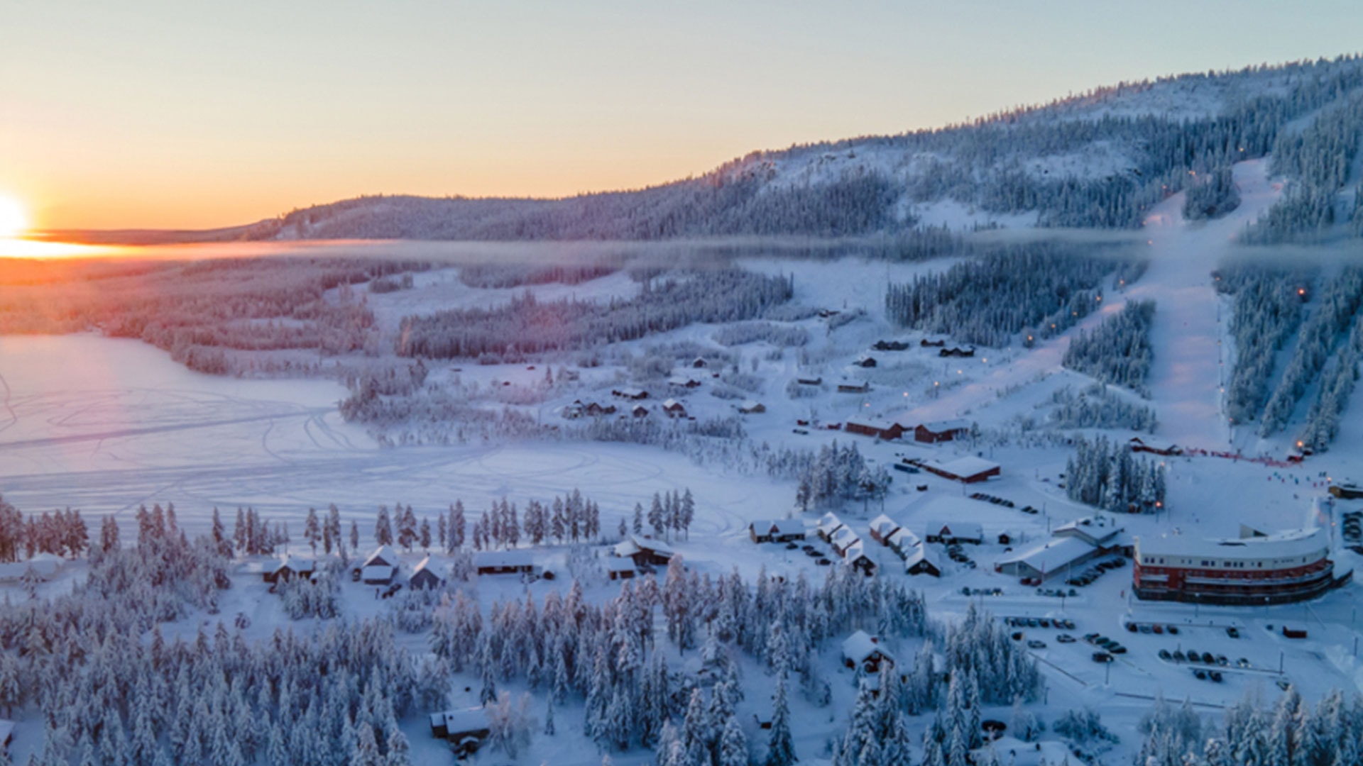 Vinterlandskap vid skidort i Sverige, med soluppgång över snöklädda berg och skidbackar