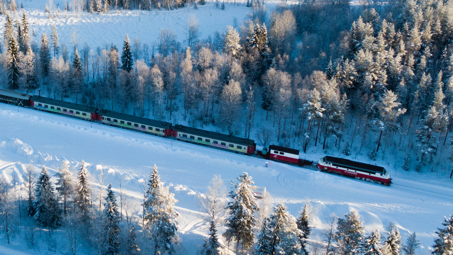 Zug fährt durch schneebedeckte Waldlandschaft in Schweden im Winter
