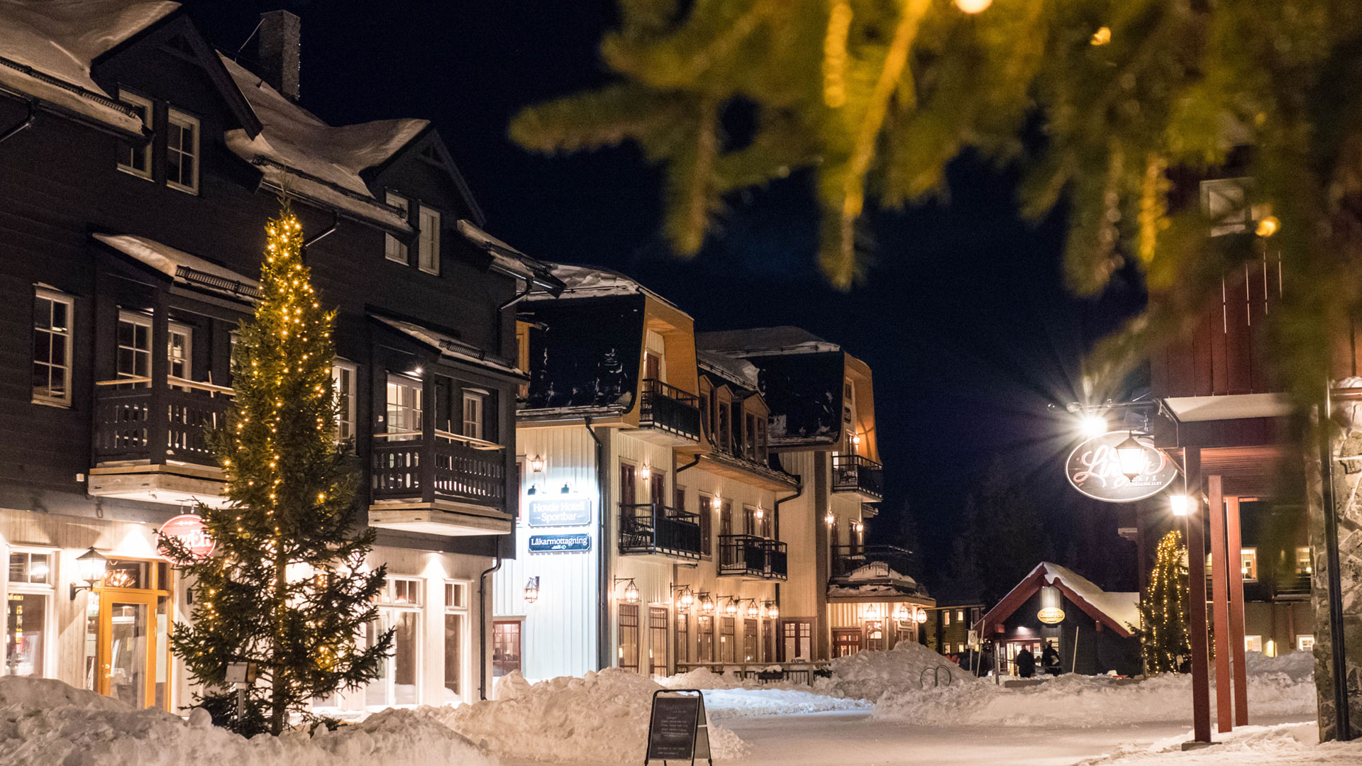 Snow-covered street in a ski resort, evening lighting, and Christmas trees with lights in a wintry Sweden
