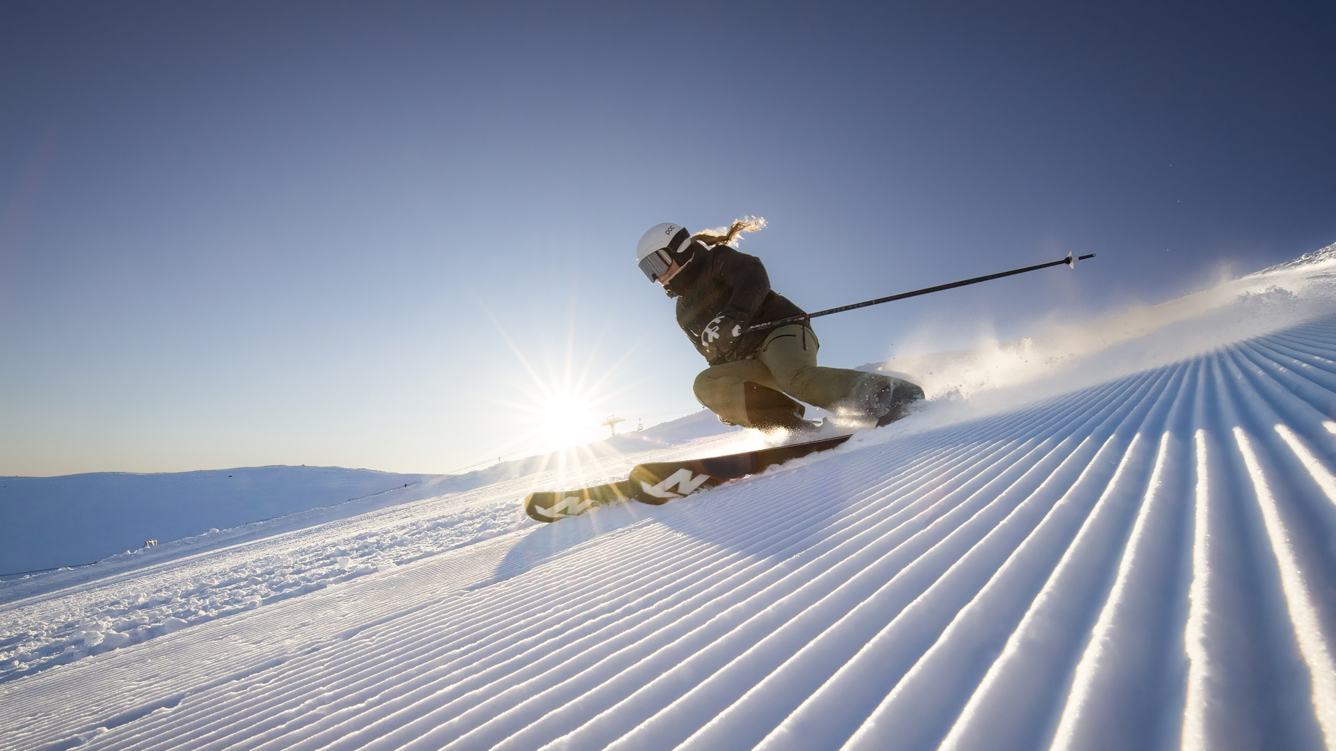 Person åker skidor nerför en pist i strålande solsken