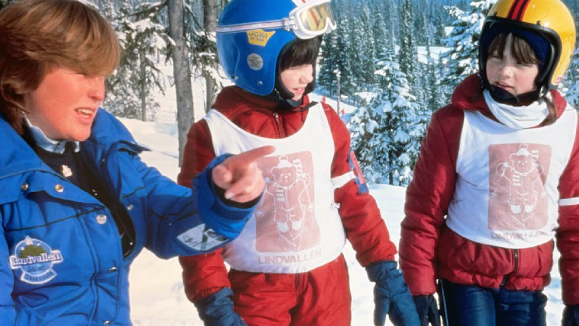 Skidinstruktör med två barn i skidutrustning på snötäckt berg, Lindvallen skidskola, Sälen, Sverige