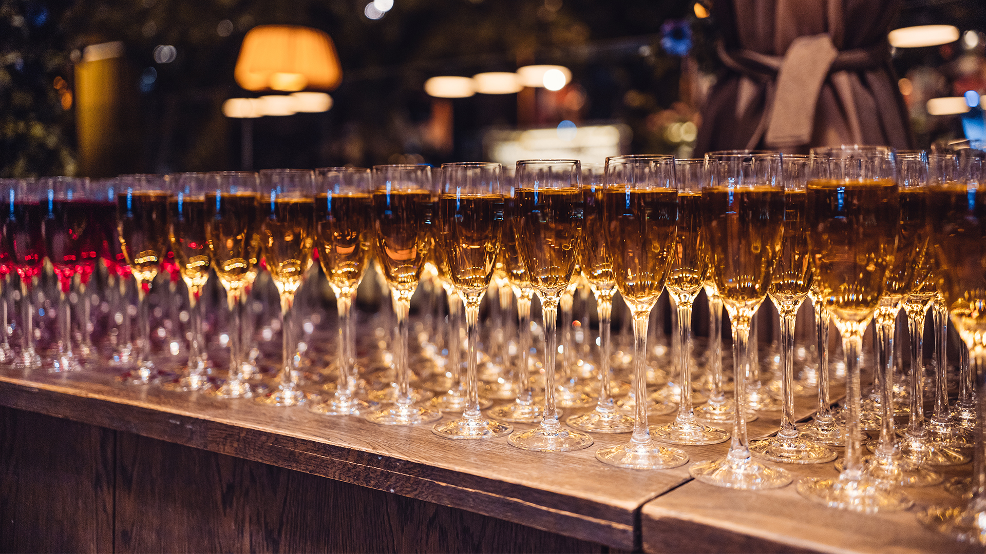 Rader av fyllda champagneglas uppställda på ett träbord i en elegant festmiljö