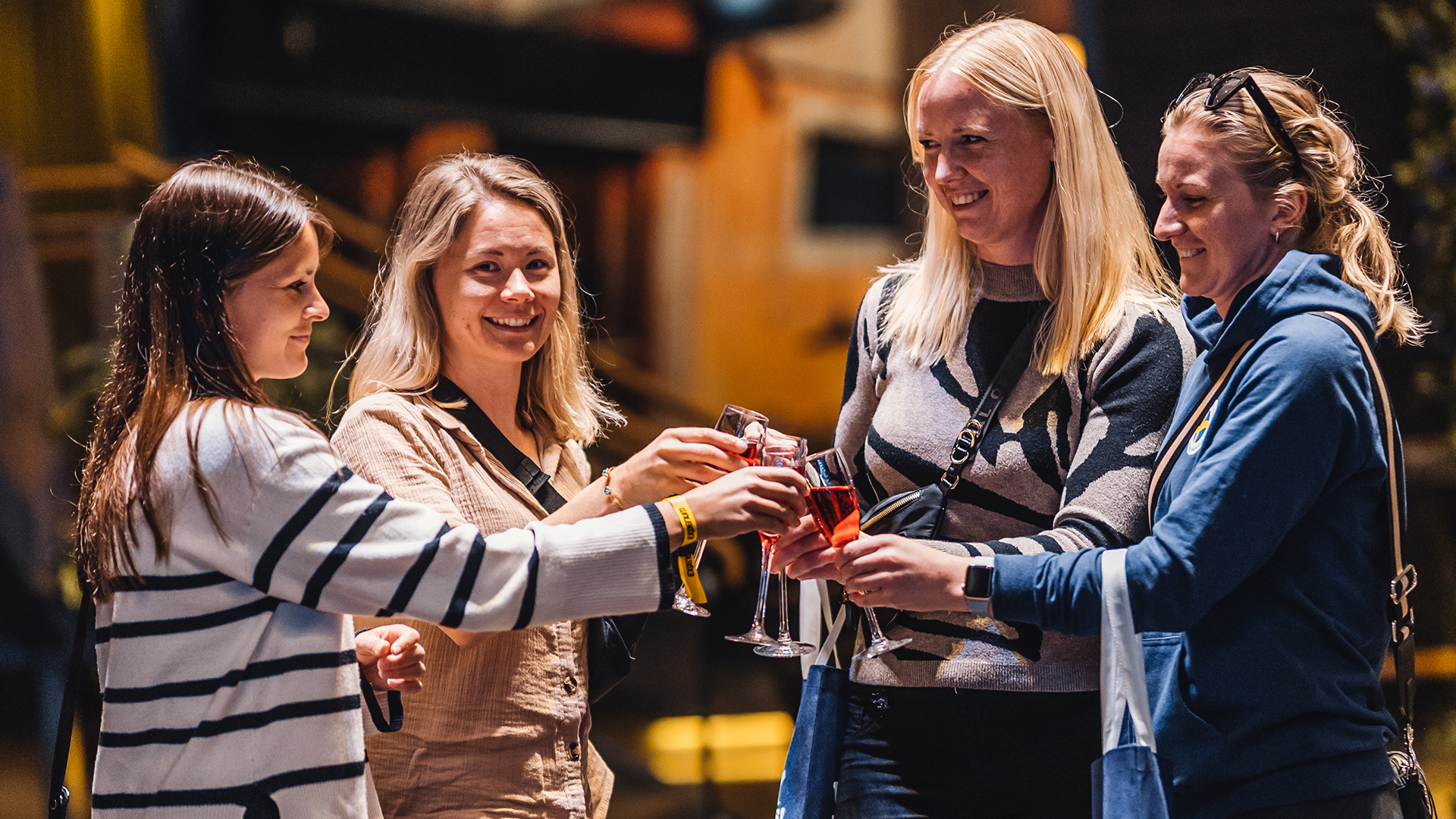Fyra kvinnor skålar med drinkar i festlig miljö