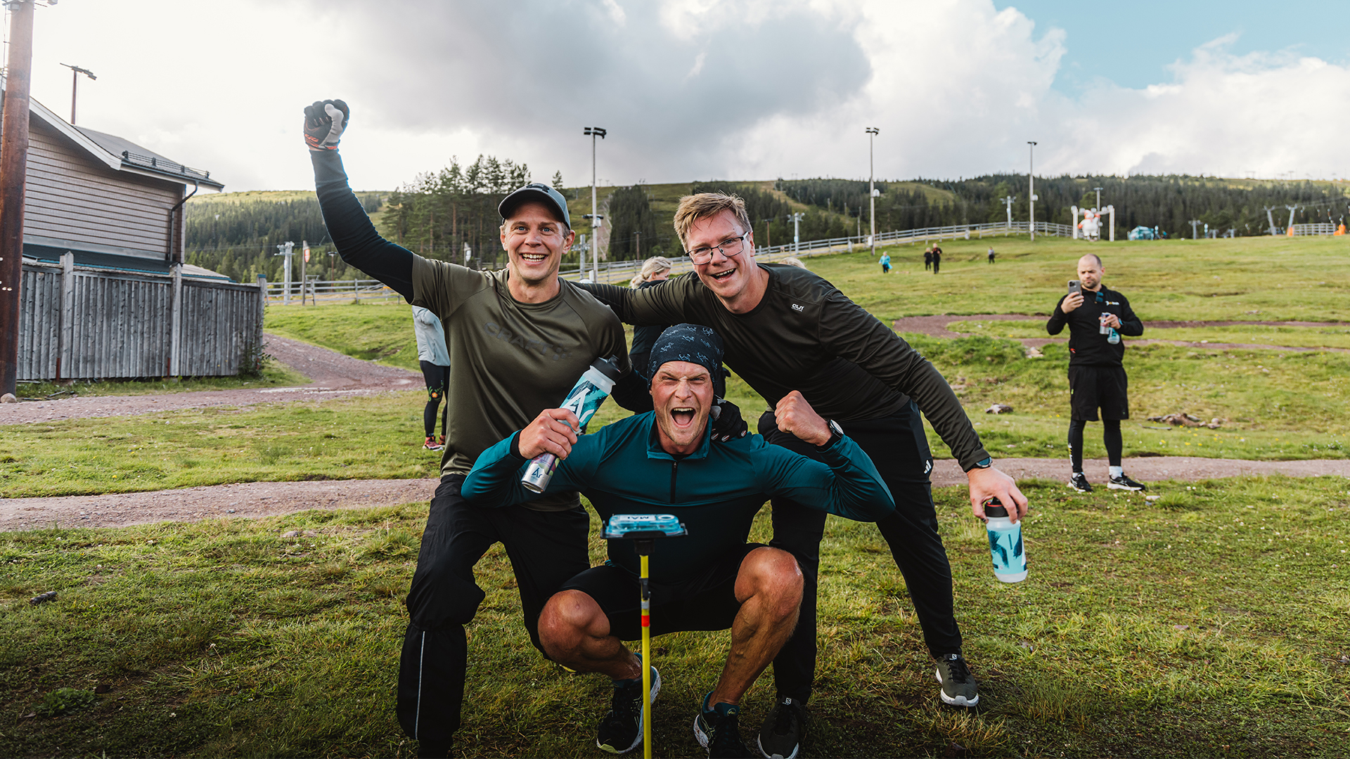 Tre glada personer deltar i teambuilding utomhus efter ett träningslopp i en naturskön park.
