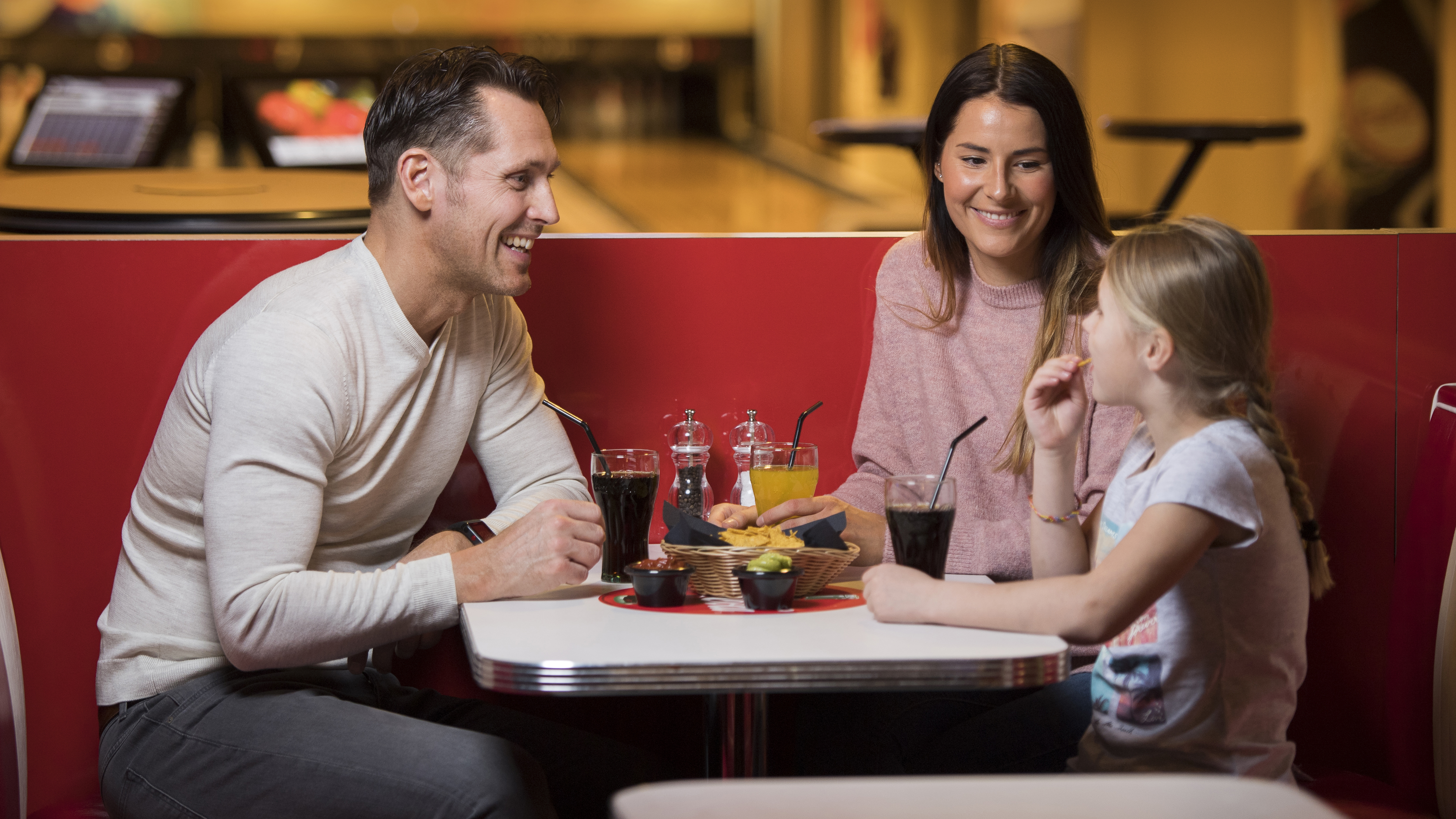 Familj äter tillsammans på en restaurang, med glad stämning och snacks på bordet