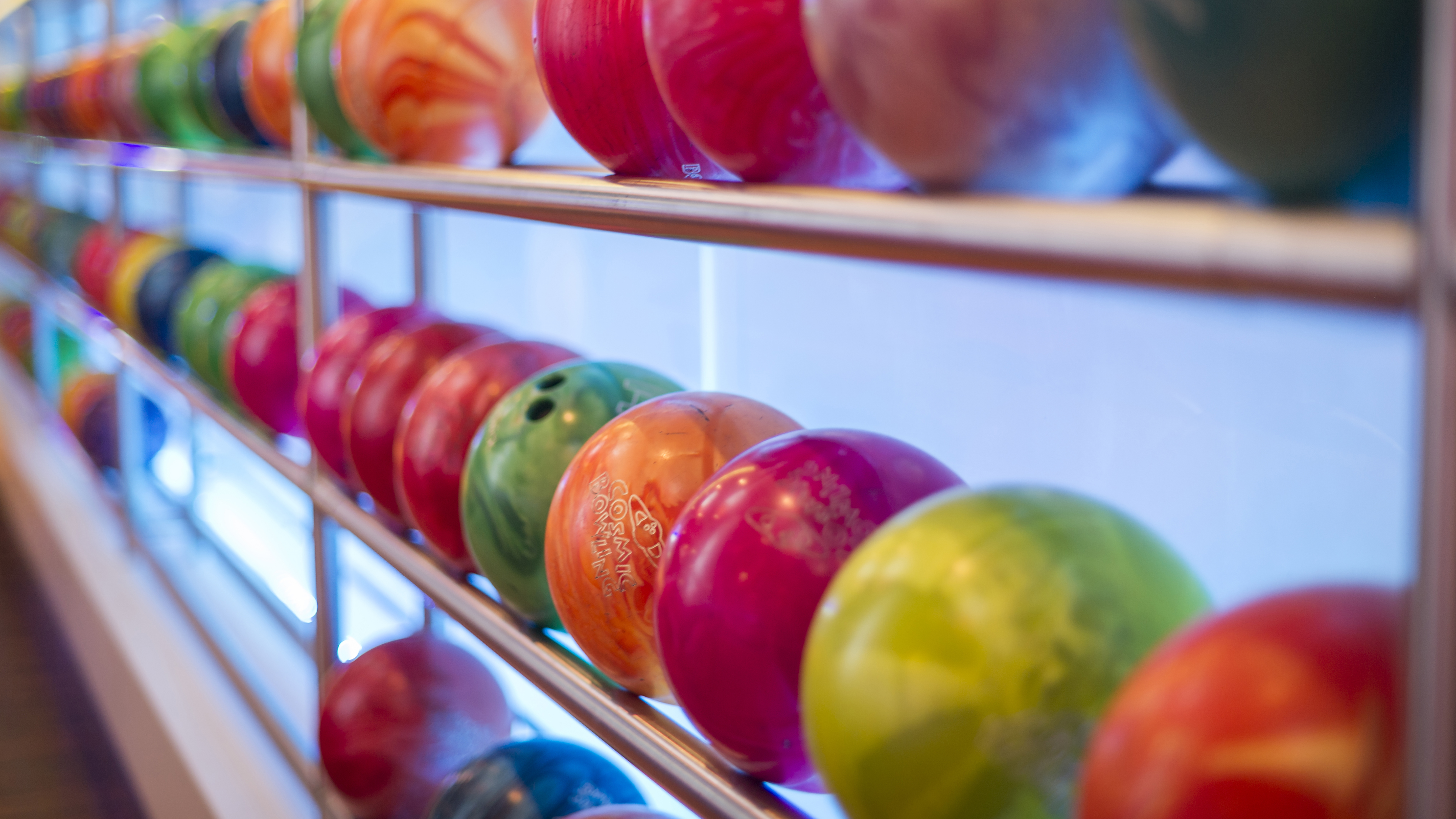 Bowlingklot i olika färger på en hylla i en bowlinghall