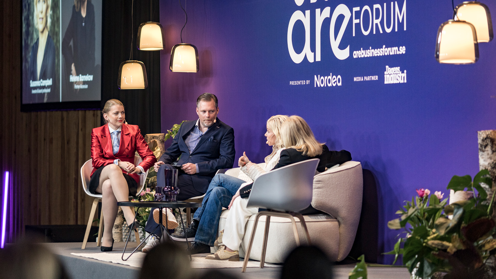 Fyra personer deltar i en paneldiskussion på Åre Business Forum. De sitter på scenen framför en blå bakgrund med forumets logga