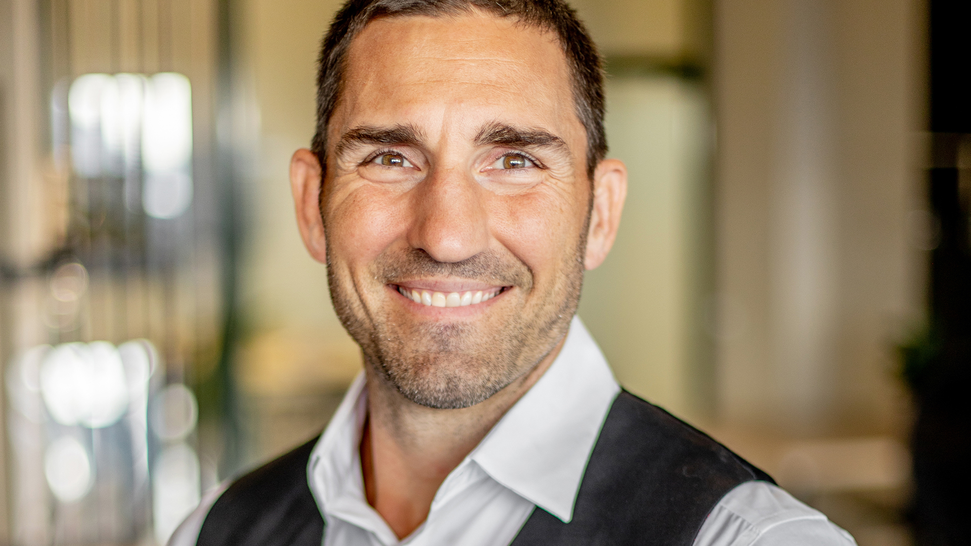 Leende man i skjorta och väst i kontorsmiljö