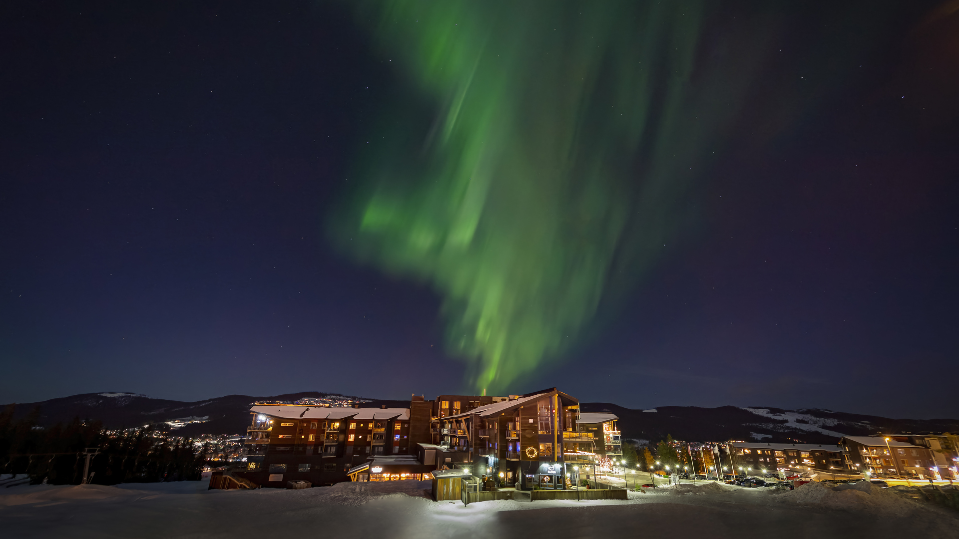 Norrsken över fjällhotell på vinternatten i Sverige