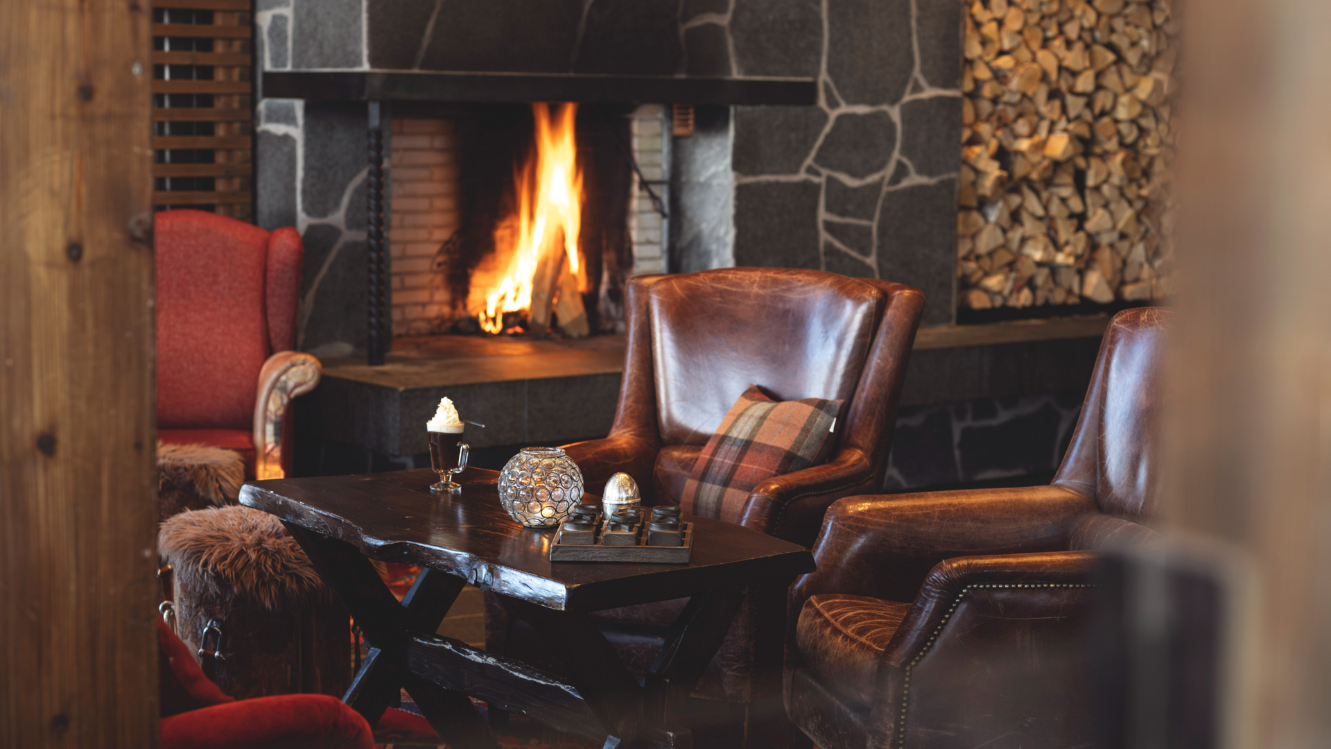 Mysig stuga med öppen spis och bekväma fåtöljer i rustik inredning