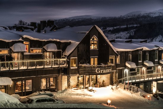 Schneebedecktes Hotel Granen in Åre, Schweden, beleuchtet am Abend mit Bergen im Hintergrund