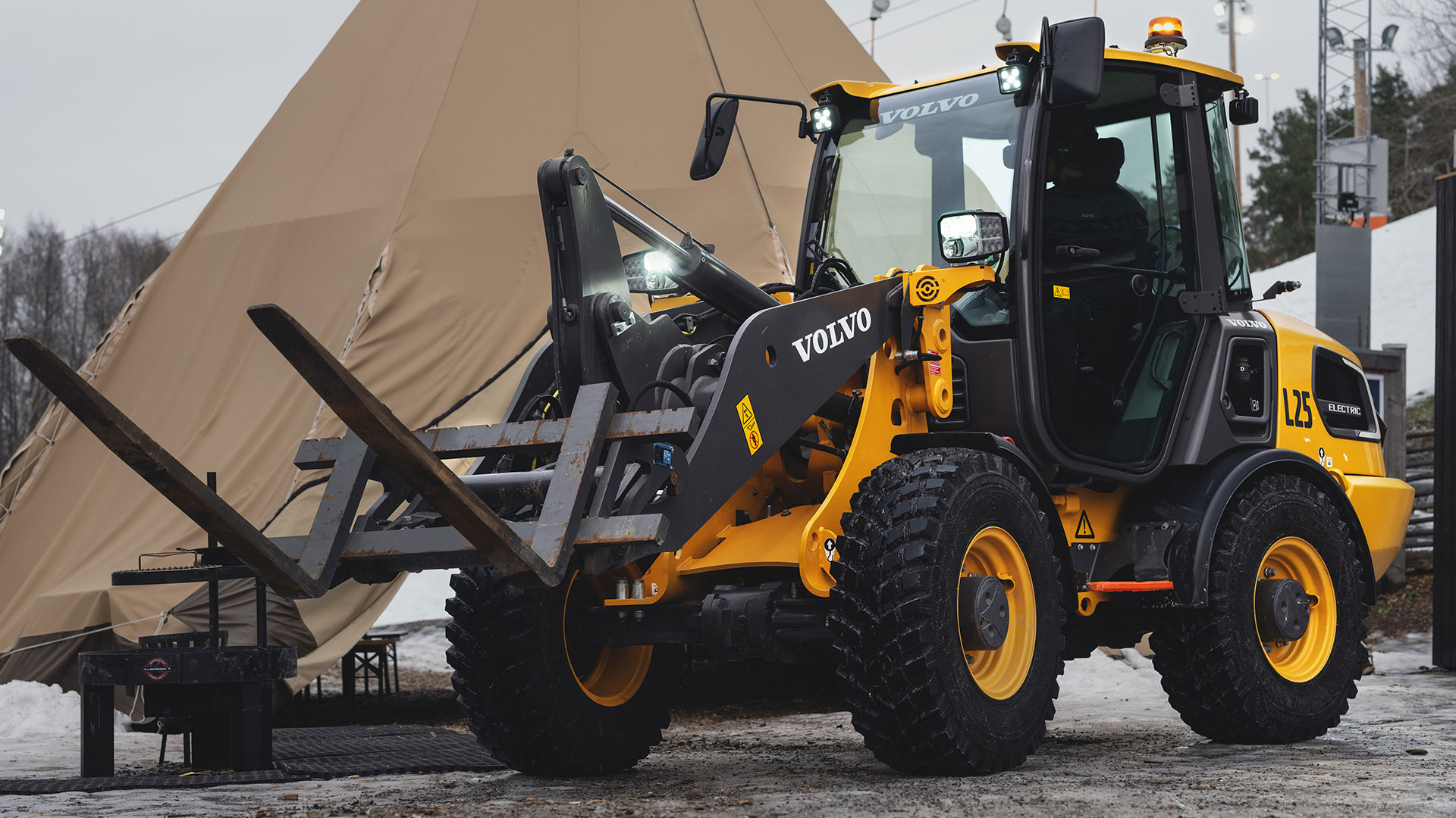 Gul Volvo L25 elektrisk hjullastare utomhus bredvid ett tält, redo för användning på byggarbetsplats