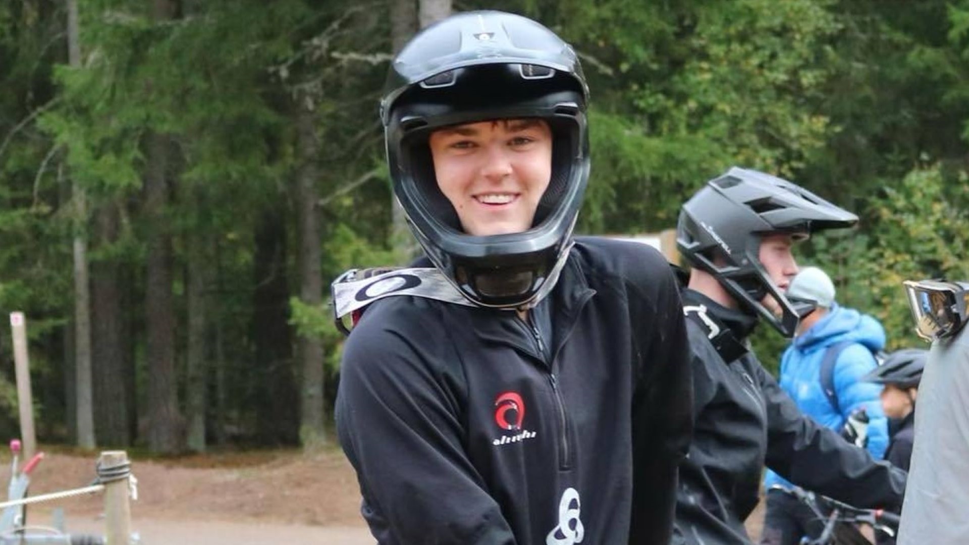 Ung mand iført mountainbikeudstyr og hjelm i skovområde, klar til cykeltur