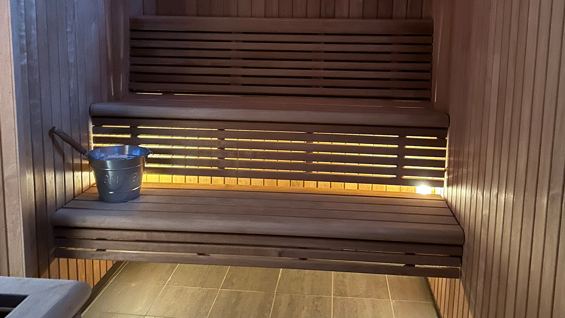 Traditionell bastuinteriör med träpanel och en hink på bänken