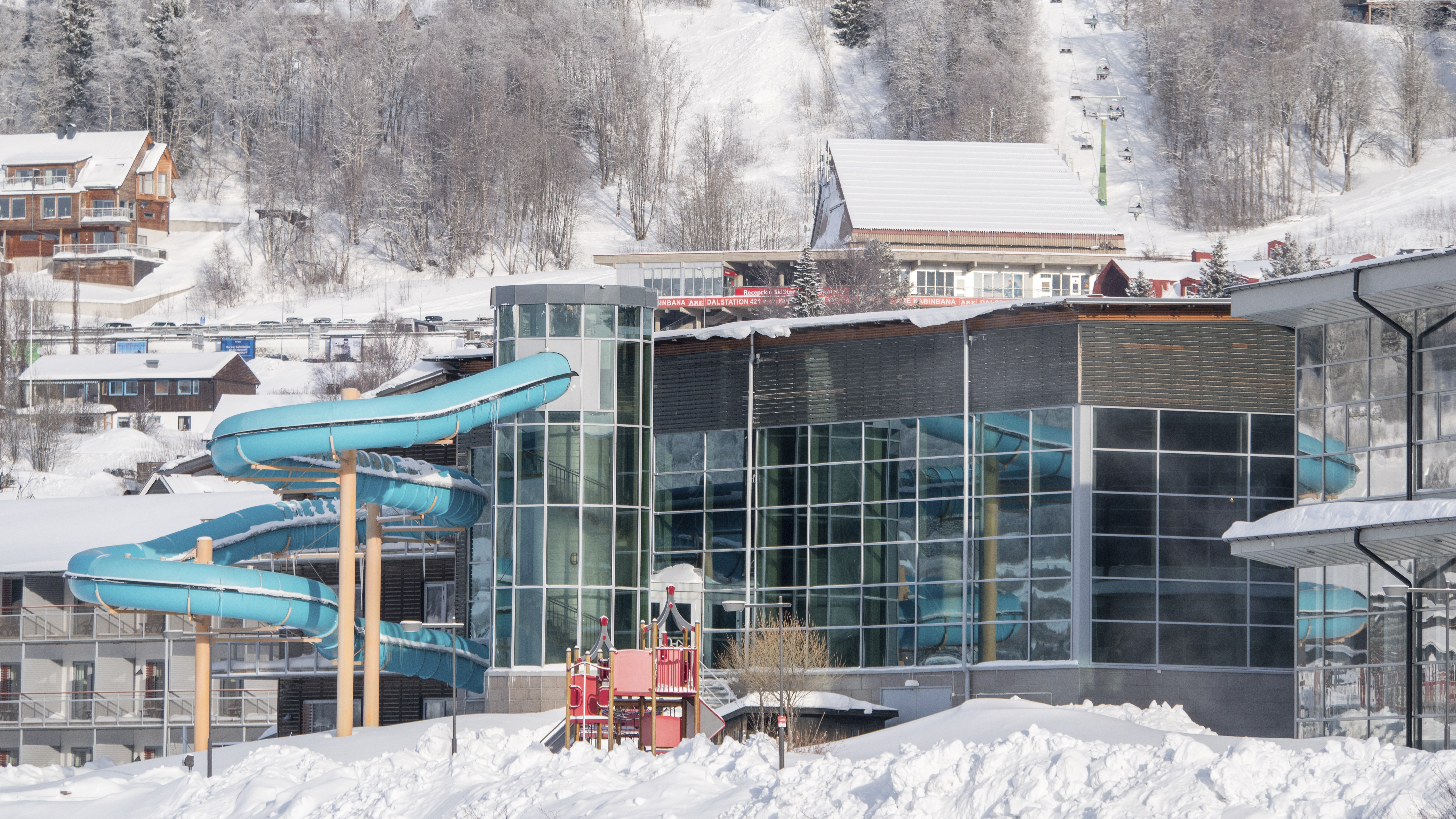 Moderne Schwimmbäder mit Wasserrutsche in verschneiter Berglandschaft