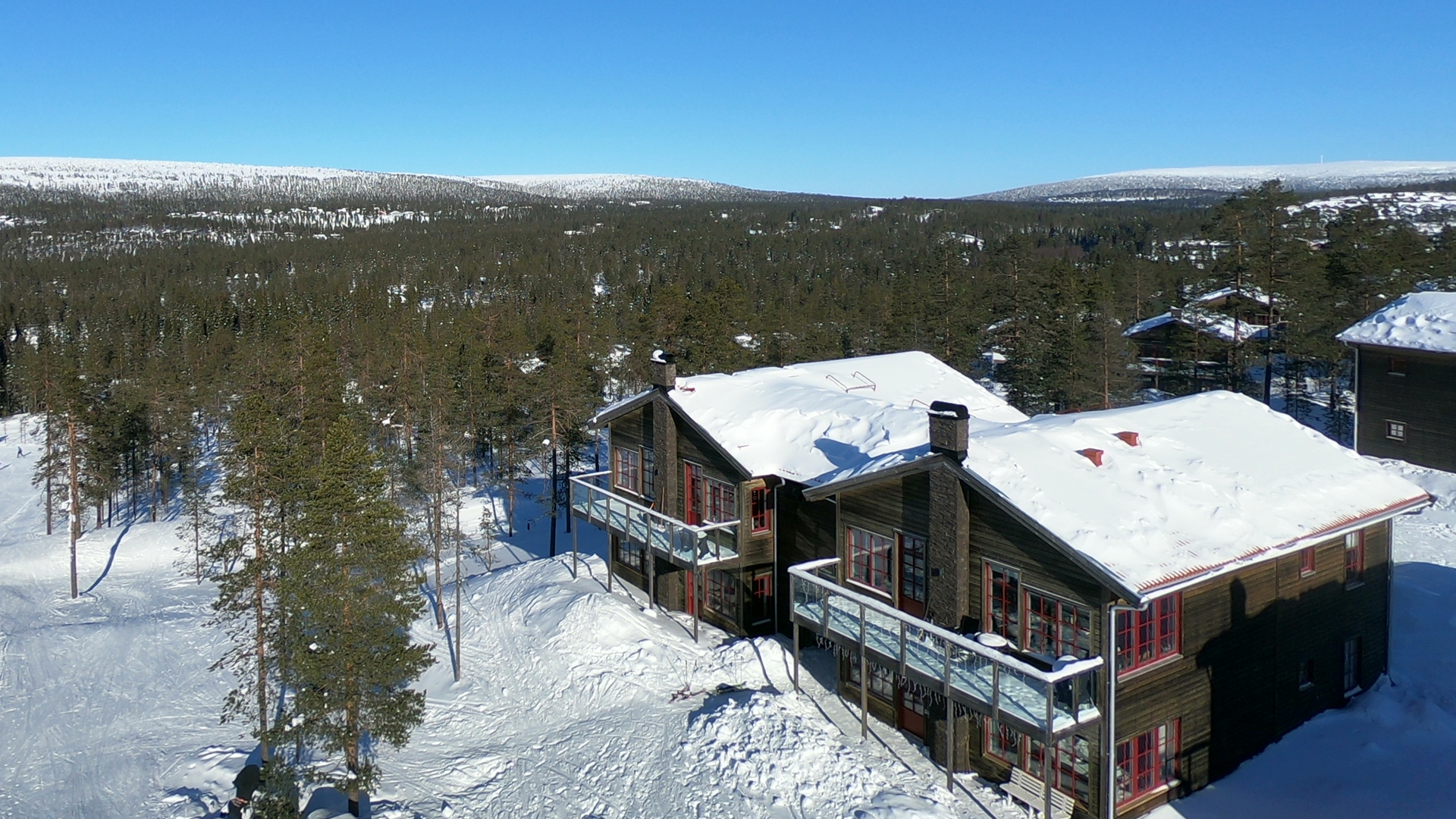 Snødekt fjellhytte blant vintergrønn furuskog i avsidesliggende svensk natur