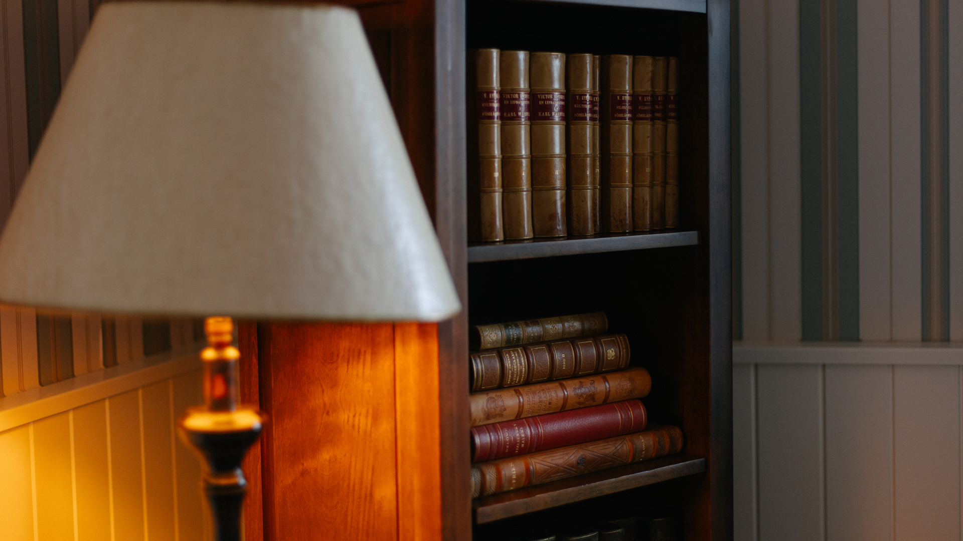 Läslampa bredvid en bokhylla med inbundna böcker i en mysig läshörna