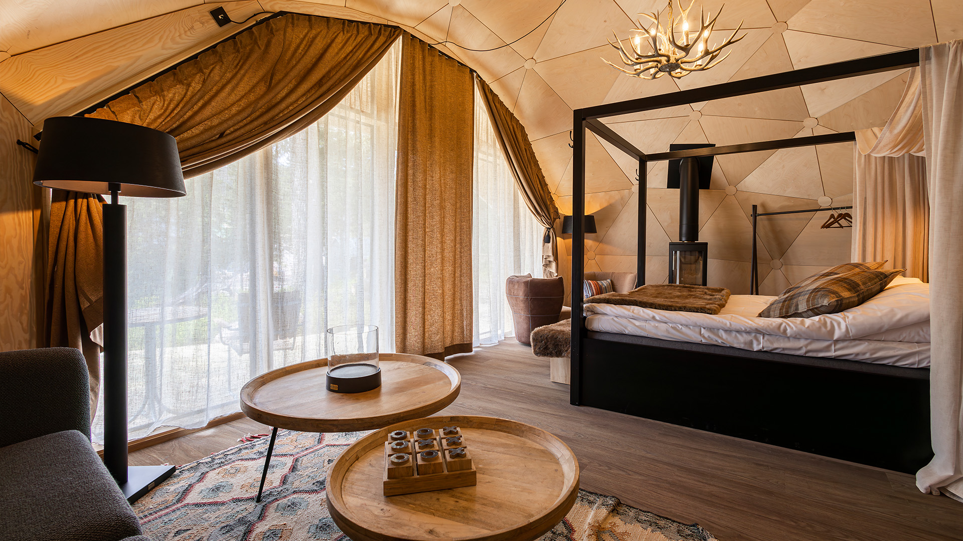 Lyxigt hotellrum med himmelsäng, moderna möbler, och stora fönster med tjocka gardiner