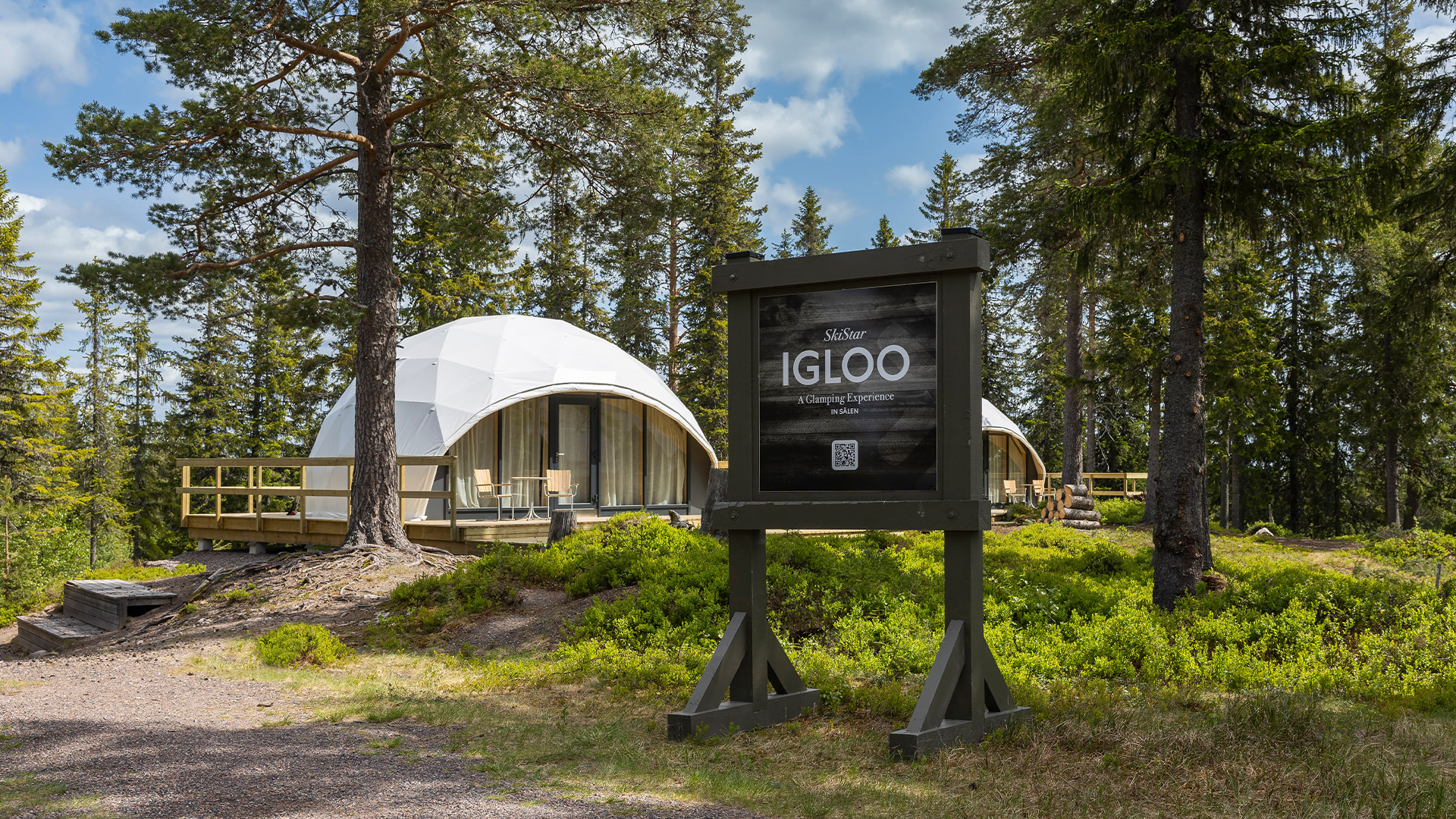 Glamping-igloos i skogsmiljö med skylt för SkiStar Igloo upplevelse
