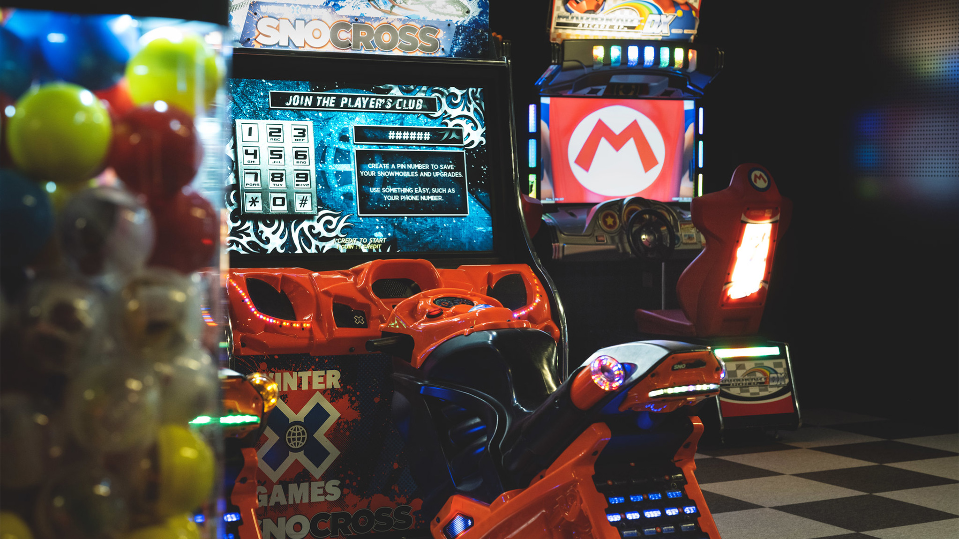 Arkadhall med SNOcross- och Mario-spelautomater, färgglada bollar till vänster