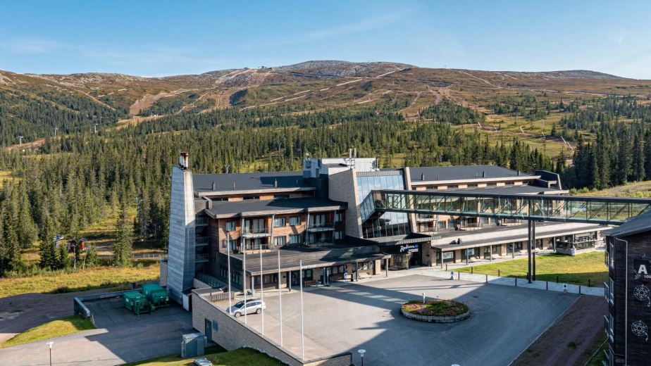 Hotell ved fjellandskap med skog i bakgrunnen, sett i Norge