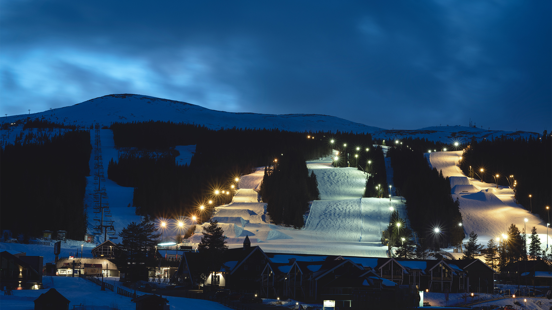 Kveldsski i Trysil, Norge, med opplyste skiløyper og snødekte fjell under en skumringshimmel