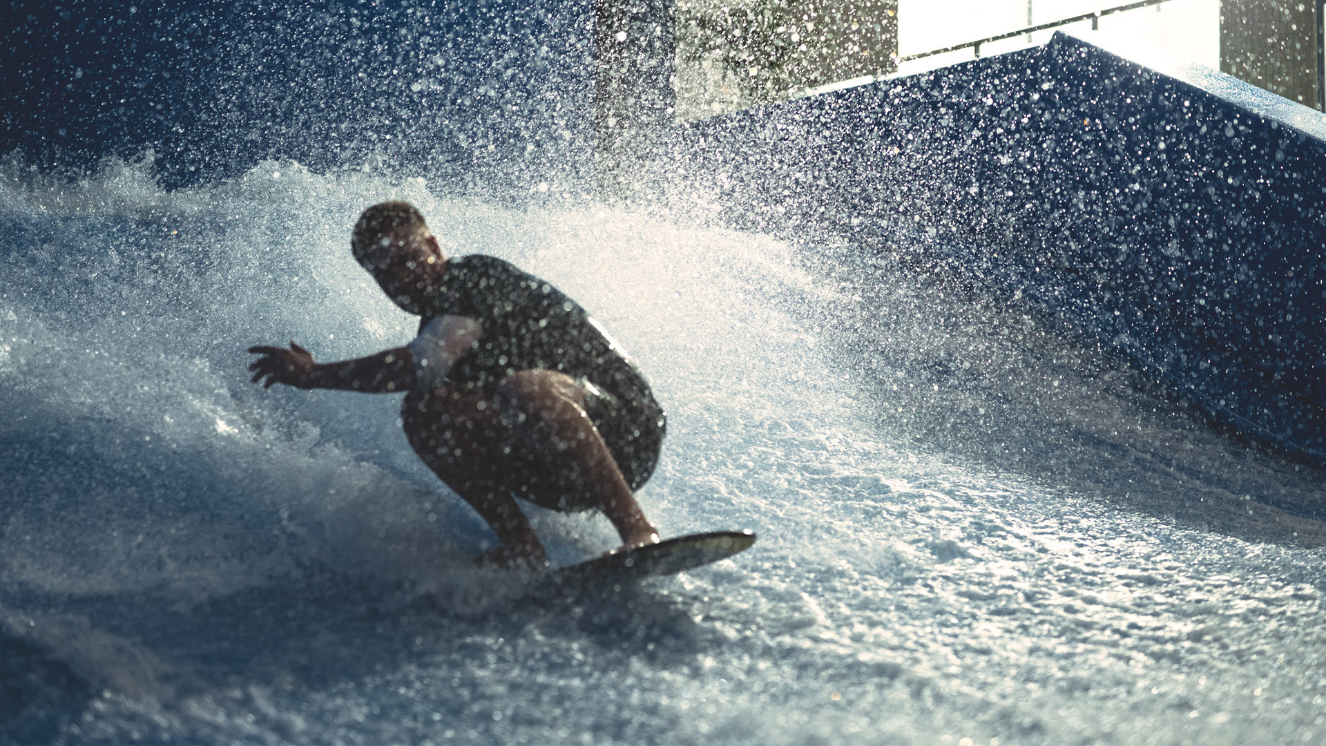 Mann surfer på en bølge innendørs, omgitt av sprutende vann