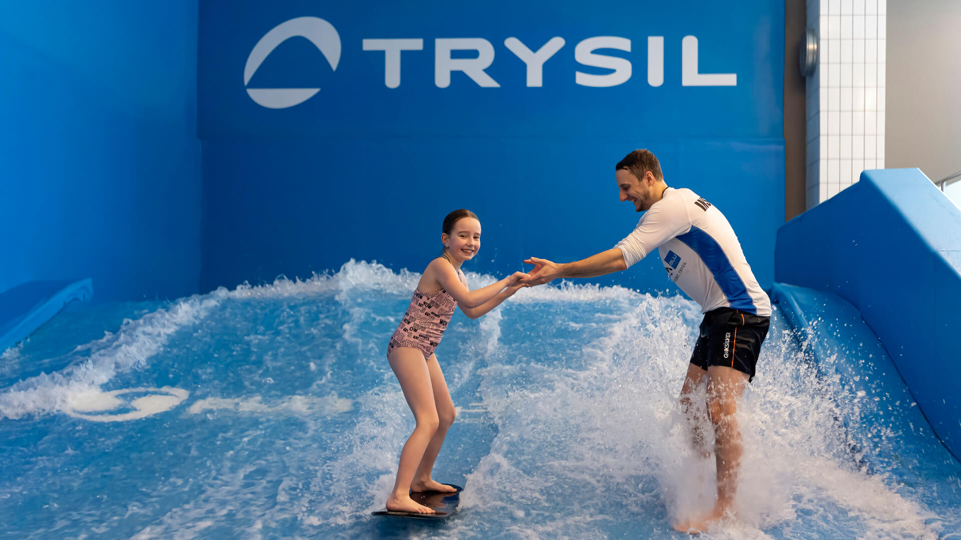 Person lærer å surfe innendørs i Trysil, Norge, med instruktørens assistanse