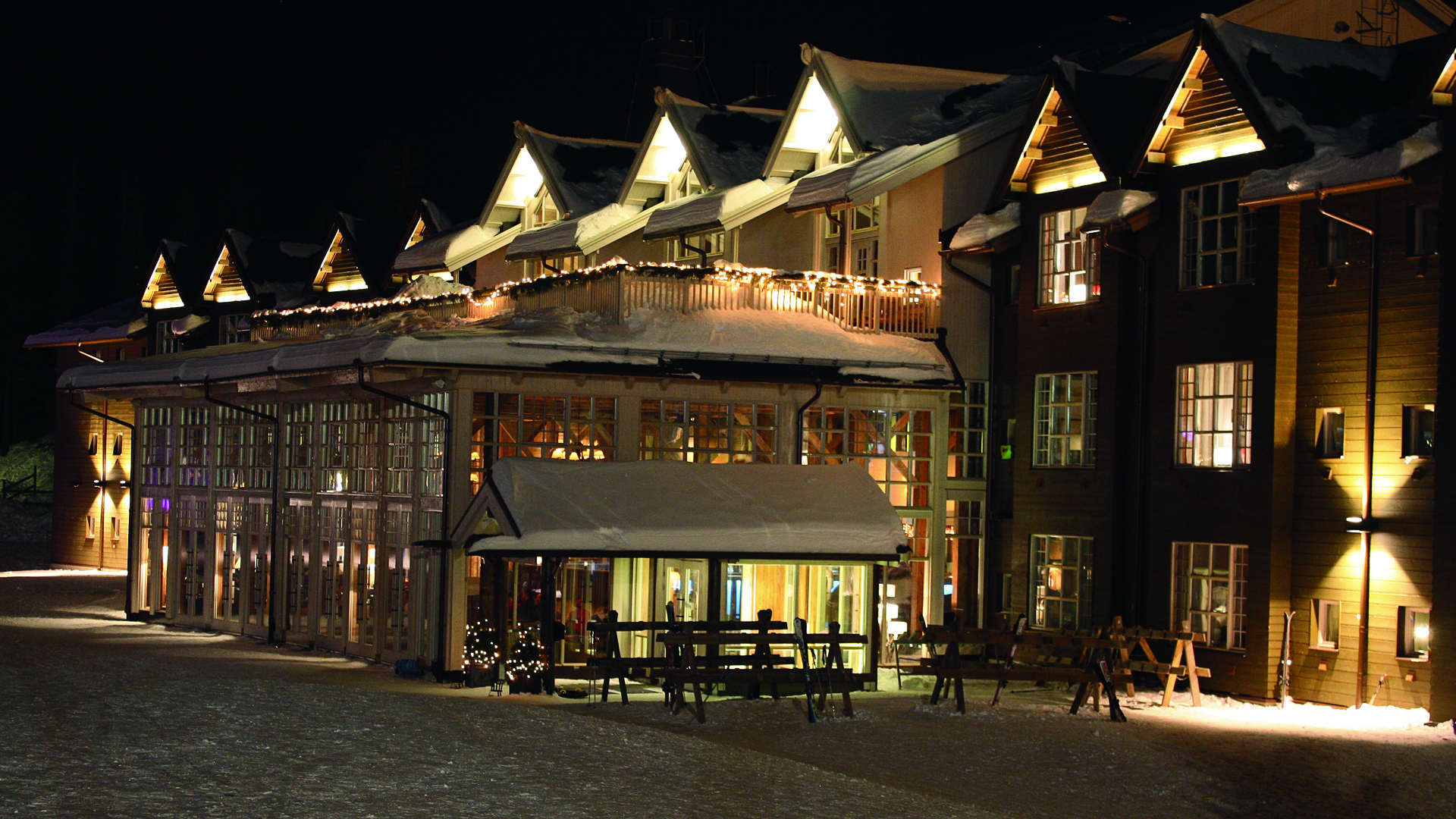 SkiStar Lodge upplyst på natten med snö på taket och mysig belysning, skog i bakgrunden