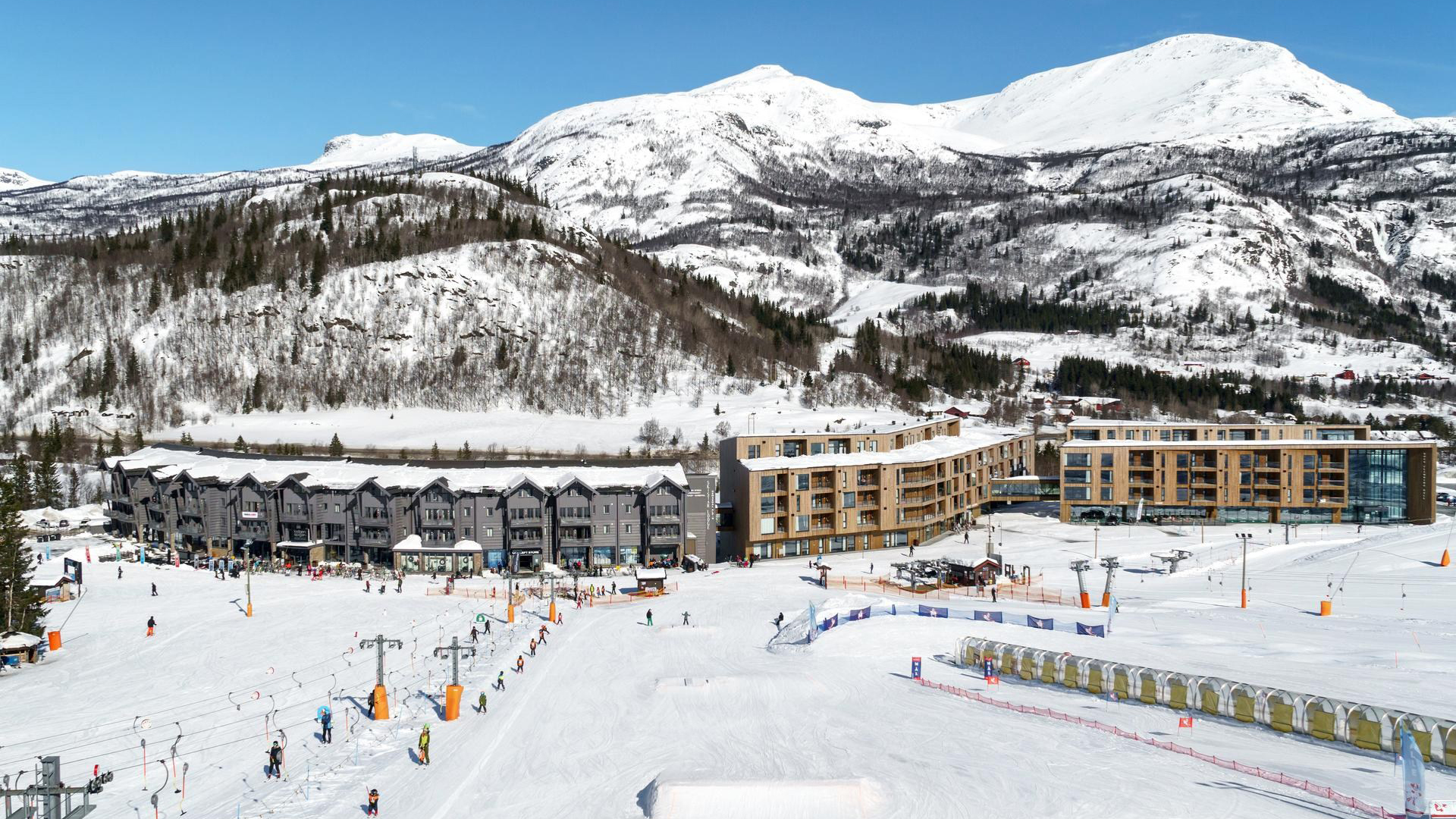 Skidanläggning med snötäckta berg och hotell vid foten av backarna, perfekta för vintersport och avkoppling