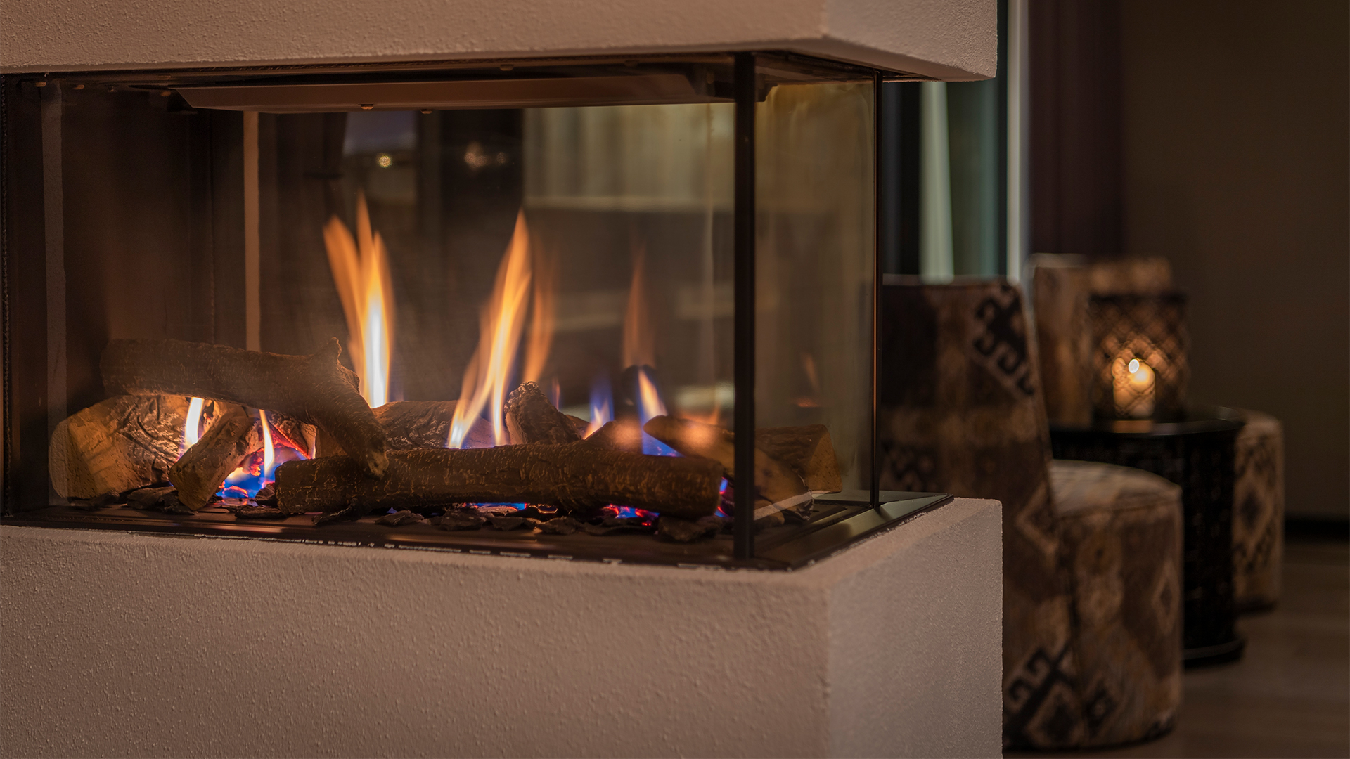 Modern öppen spis i ett elegant vardagsrum med brinnande ved, skapar en mysig atmosfär