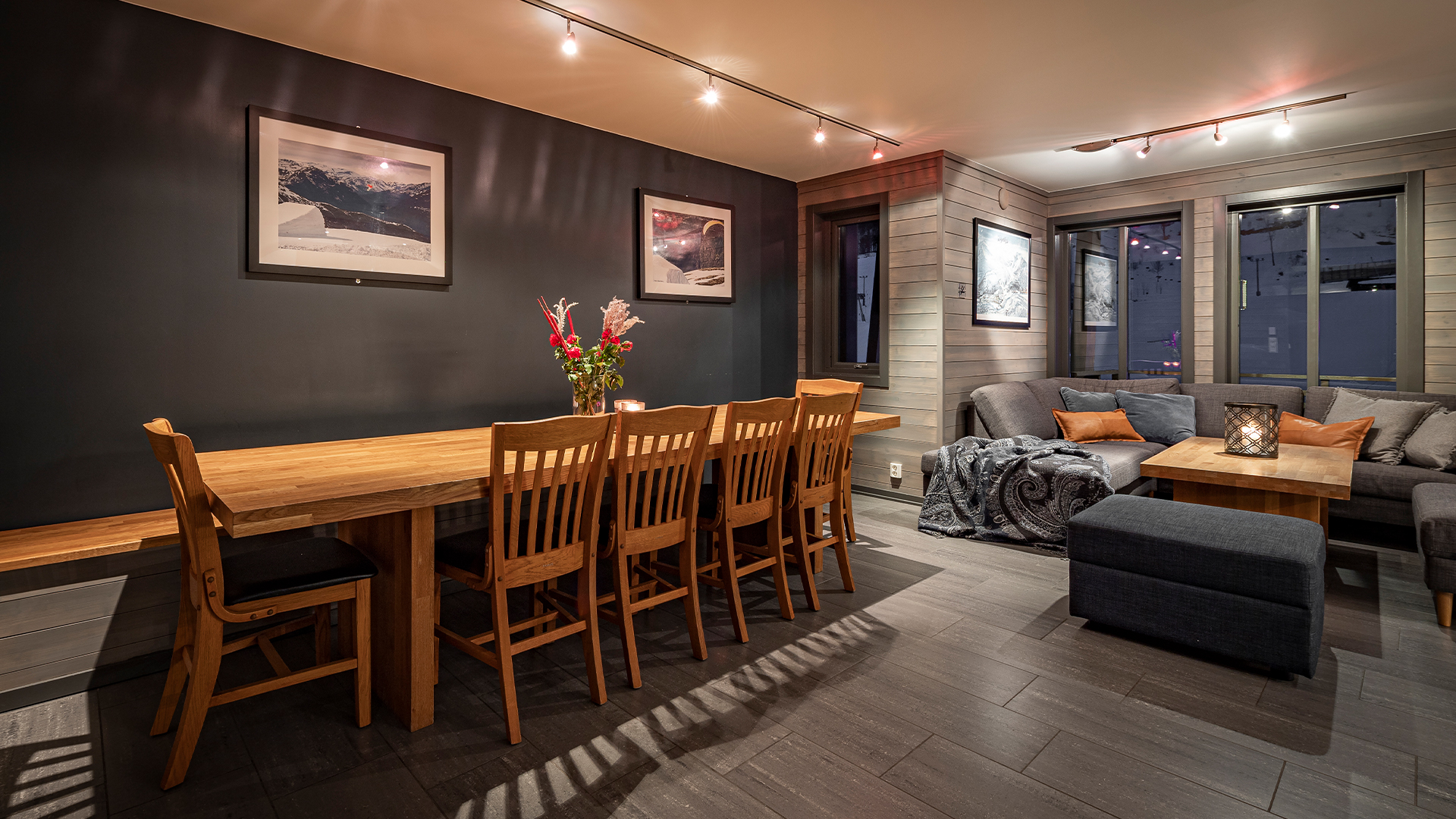 Modernt vardagsrum med matbord i trä, stolar och mysig hörnsoffa, dekorerat med blommor och konstverk på väggarna