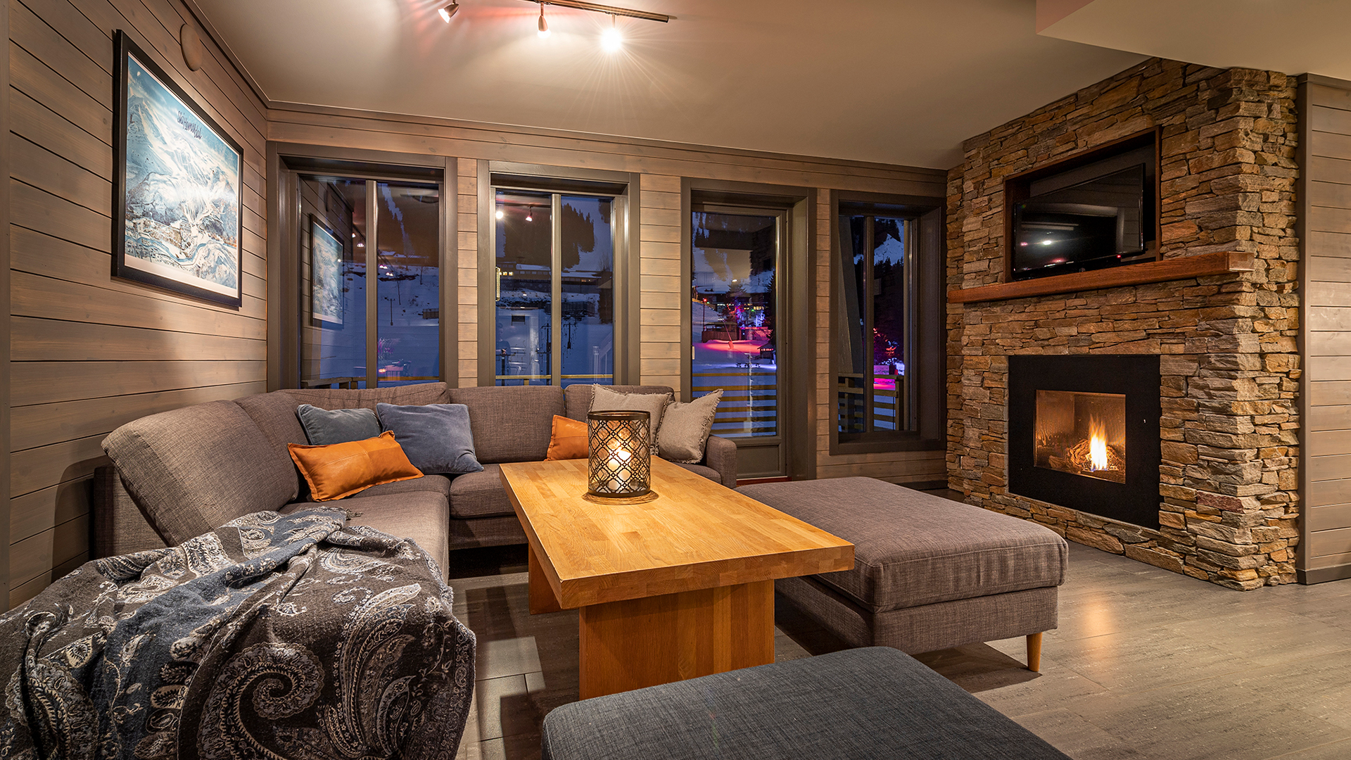 Mysigt vardagsrum med modern hörnsoffa, stenvägg med öppen spis och träbord