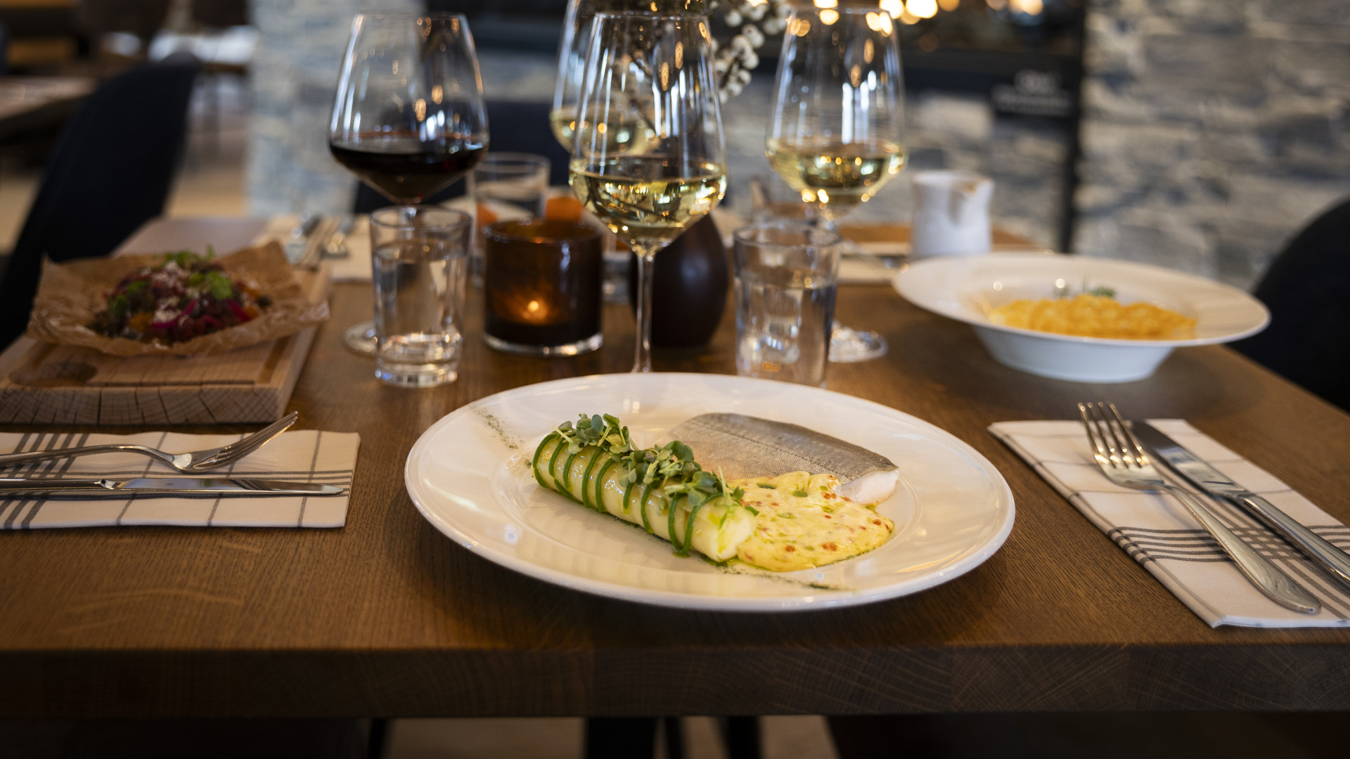 En elegant matservering med fisk, grönsaker och ett glas rött vin på en restaurang