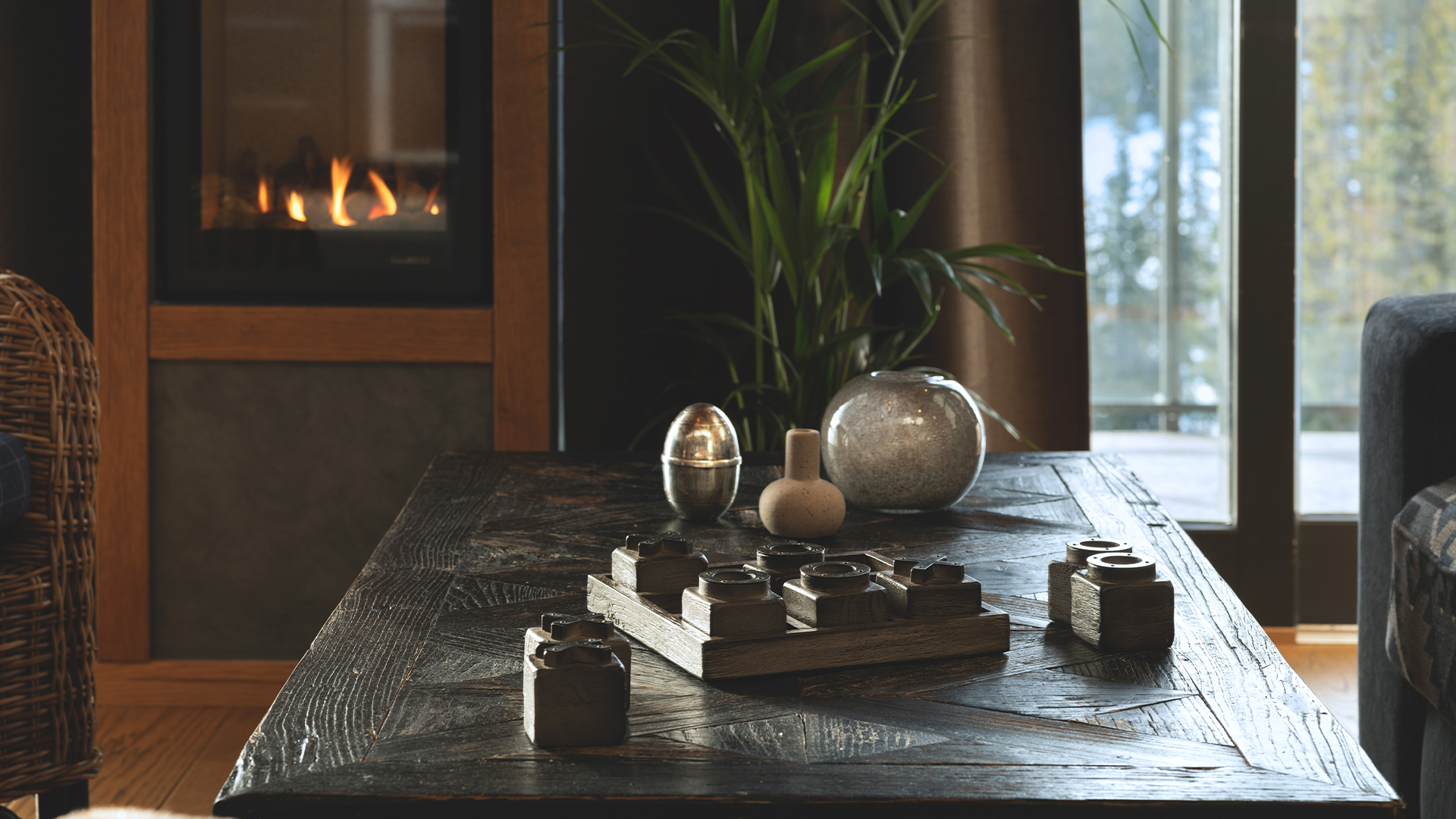 Snyggt vardagsrum med rustik träbord, dekorativa föremål och en brinnande öppen spis i bakgrunden