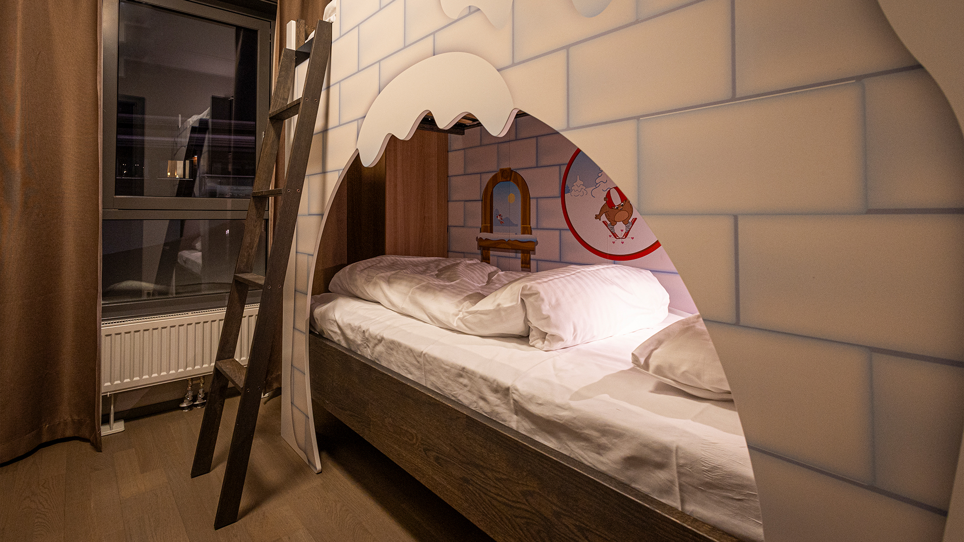 Våningssäng i barnvänligt rum med lekfull dekor och murverksdesign, bredvid fönster med mörka gardiner