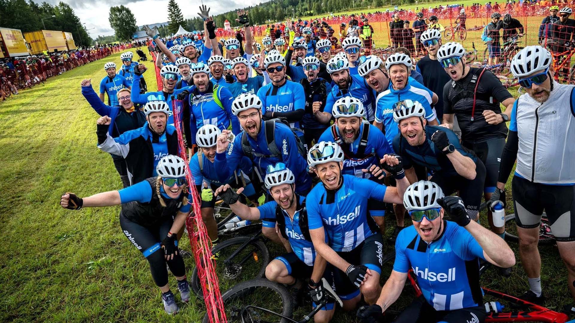 Cykellag i blåa tröjor samlade för fotot under en tävling, glad stämning på grön gräsplan