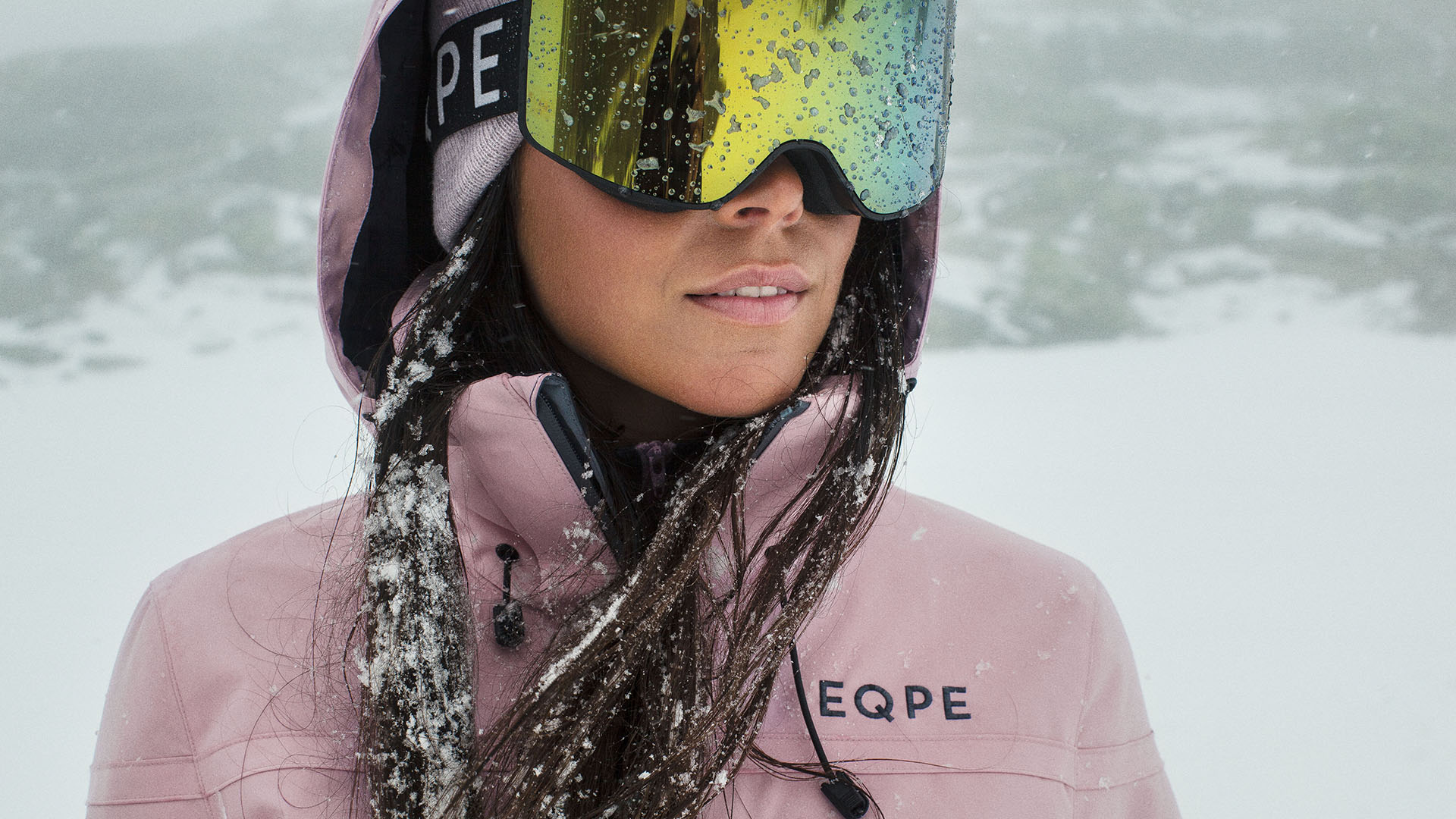 Kvinna i rosa vinterjacka och skidglasögon i snöig miljö