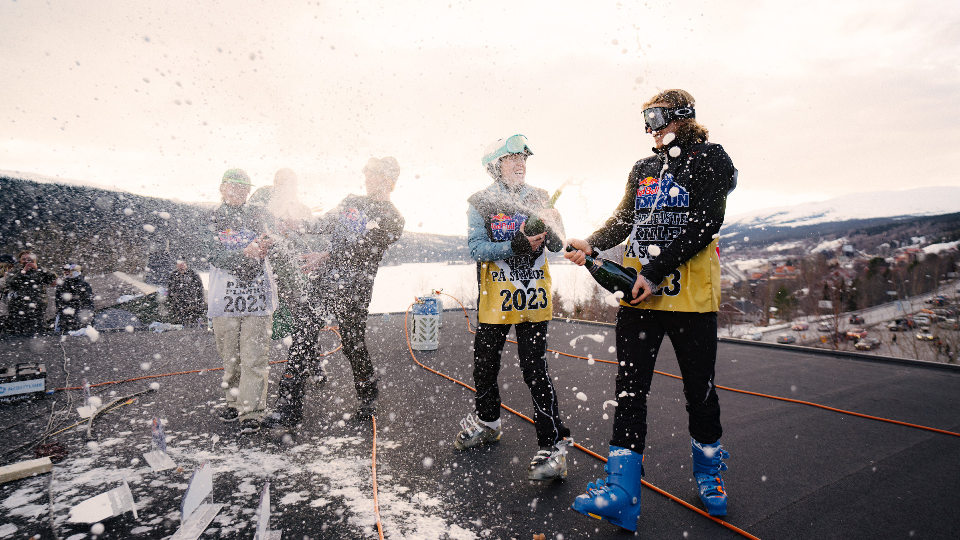 Folk fejrer med champagne under en skitur i Åre, Sverige, 2023. Sneen falder, mens de er klædt i skitøj og omgivet af bjergene