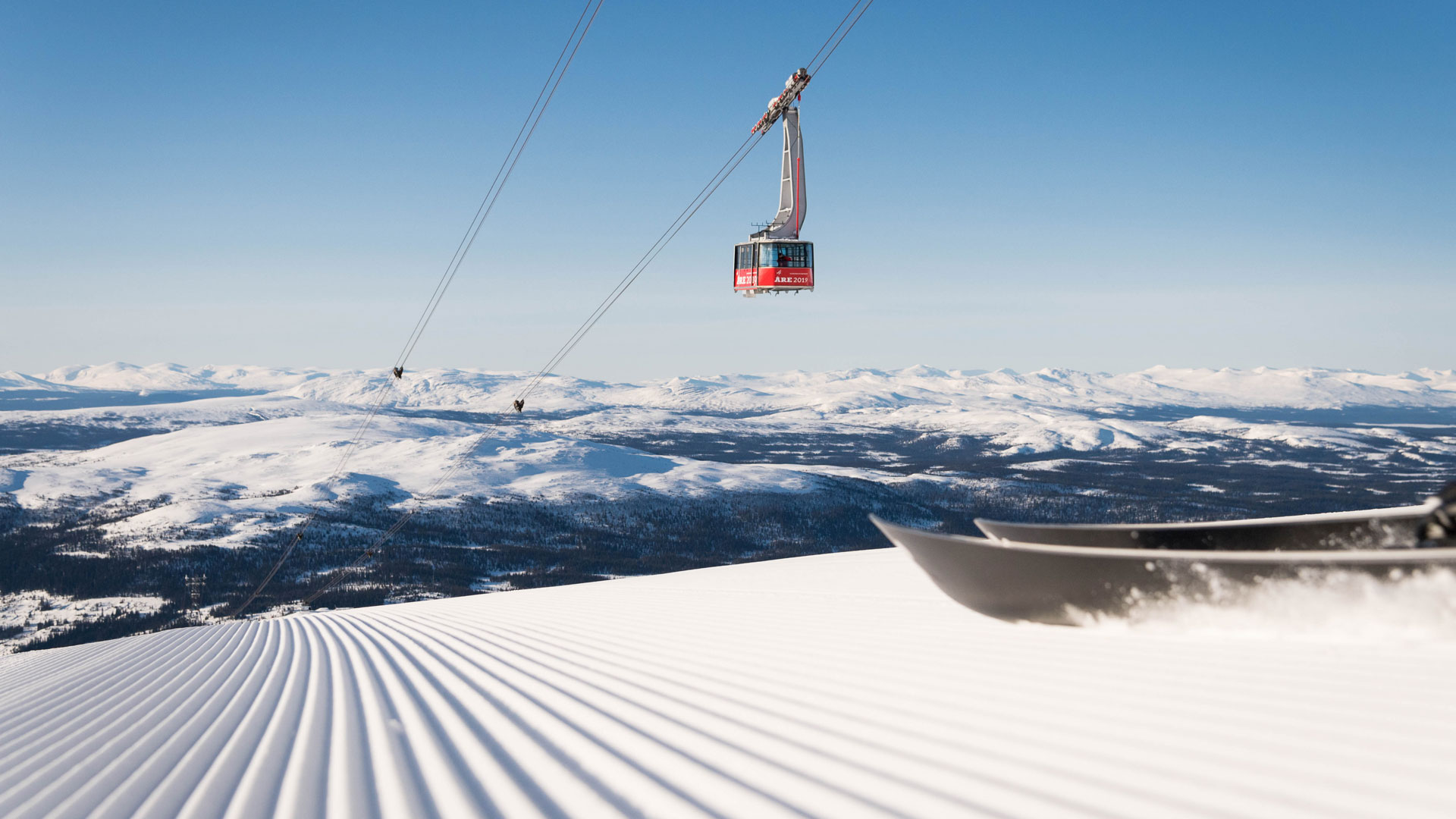 Skiløb i Åre med udsigt over sneklædte bjerge og en svævebane mod en klarblå himmel