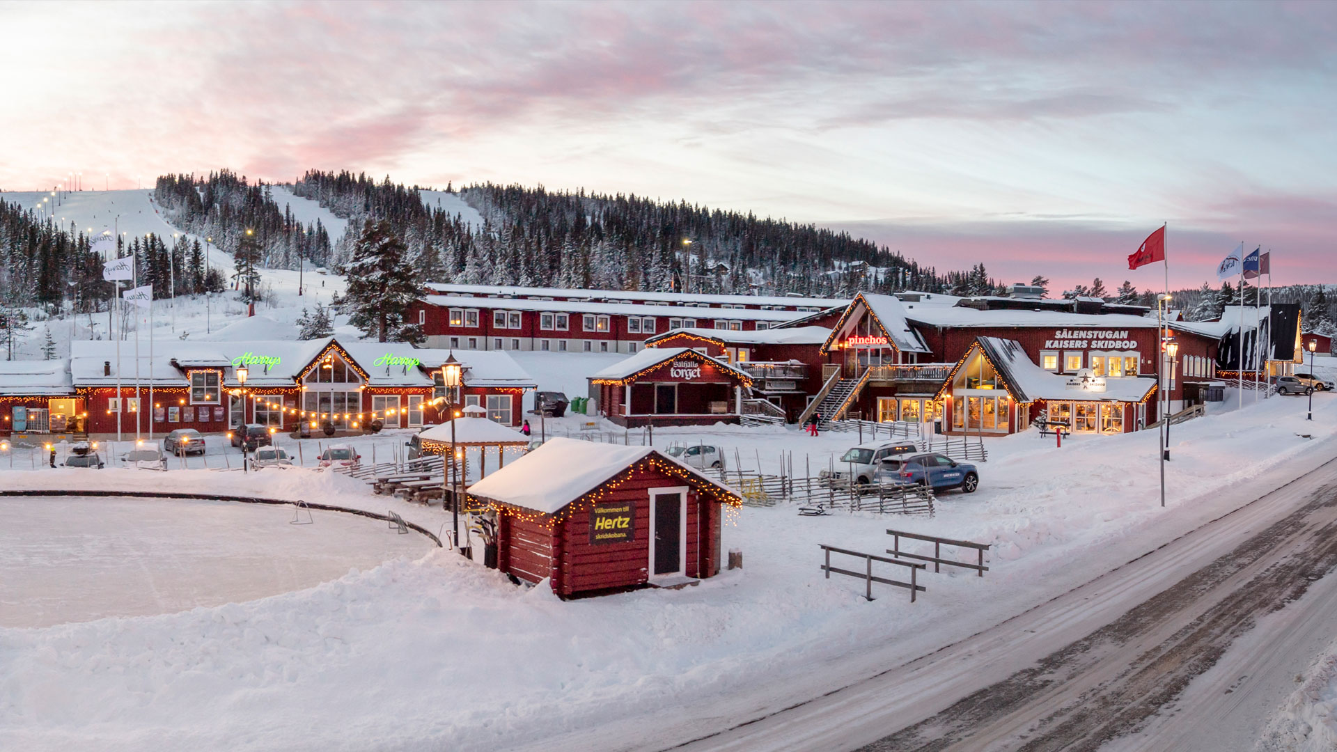 Vintervy över Sälenfjällen med snötäckta stugor och skidcenter vid solnedgång, Sverige