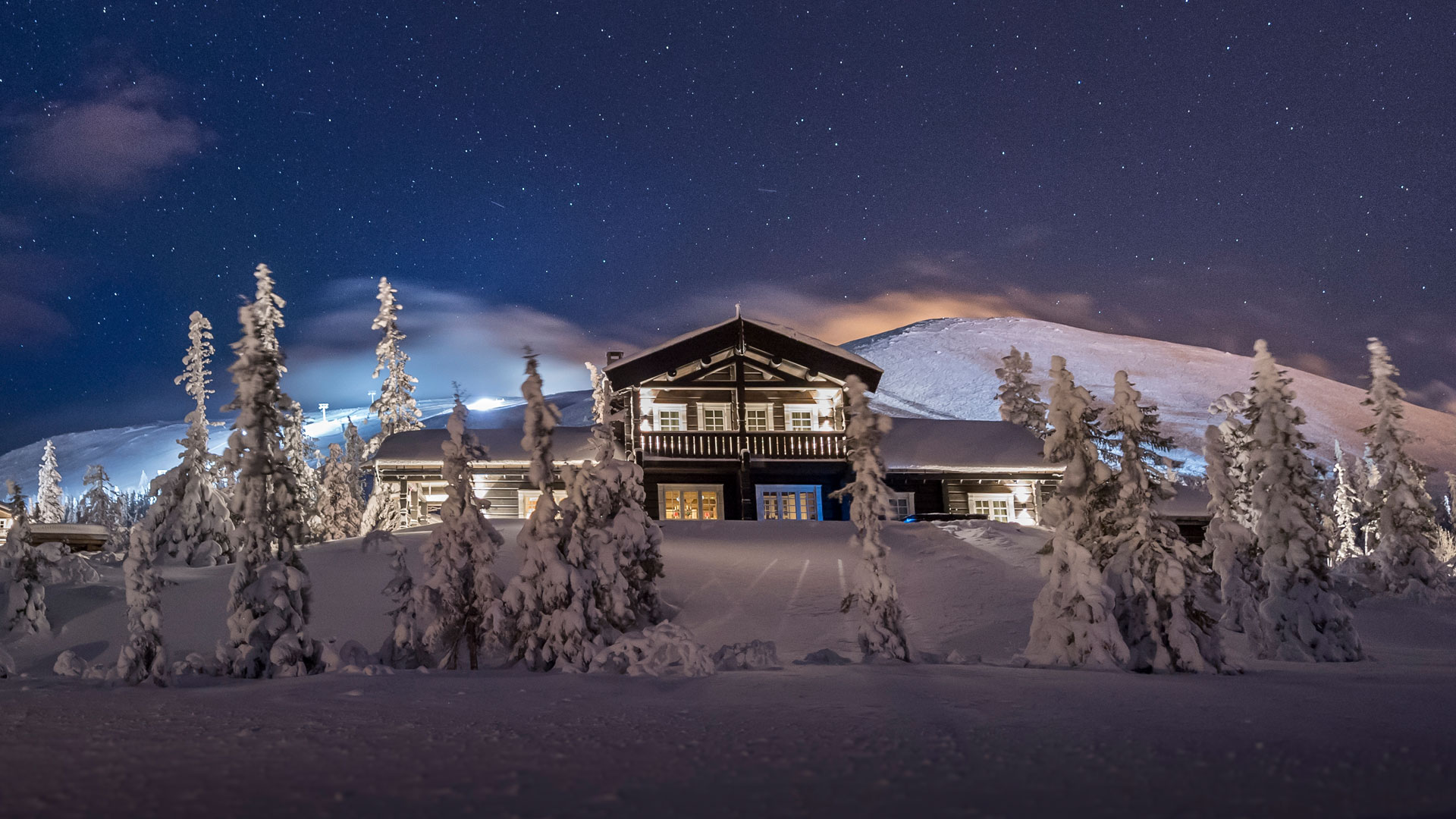Fjeldhytte i snedækket landskab under stjerneklar nattehimmel i de svenske fjelde