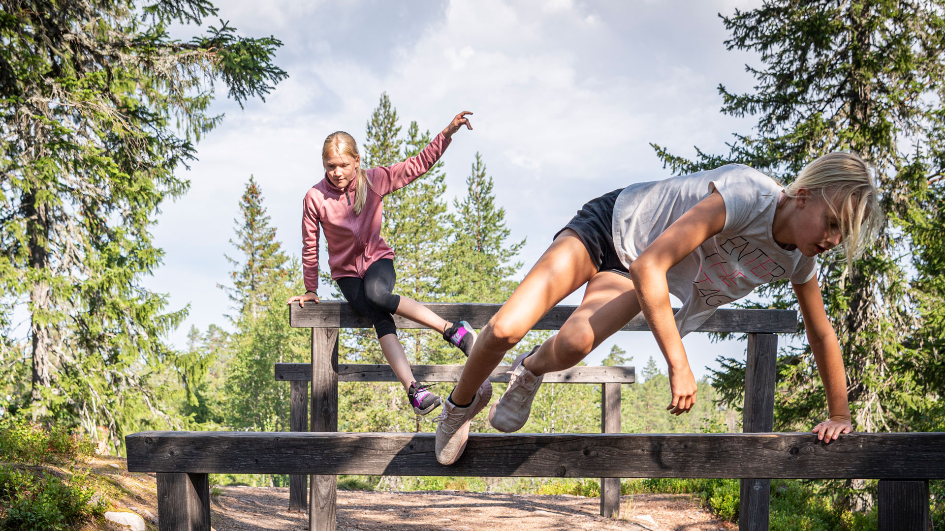 Barn som hoppar över hinder i skogen, solig dag, utomhusaktivitet
